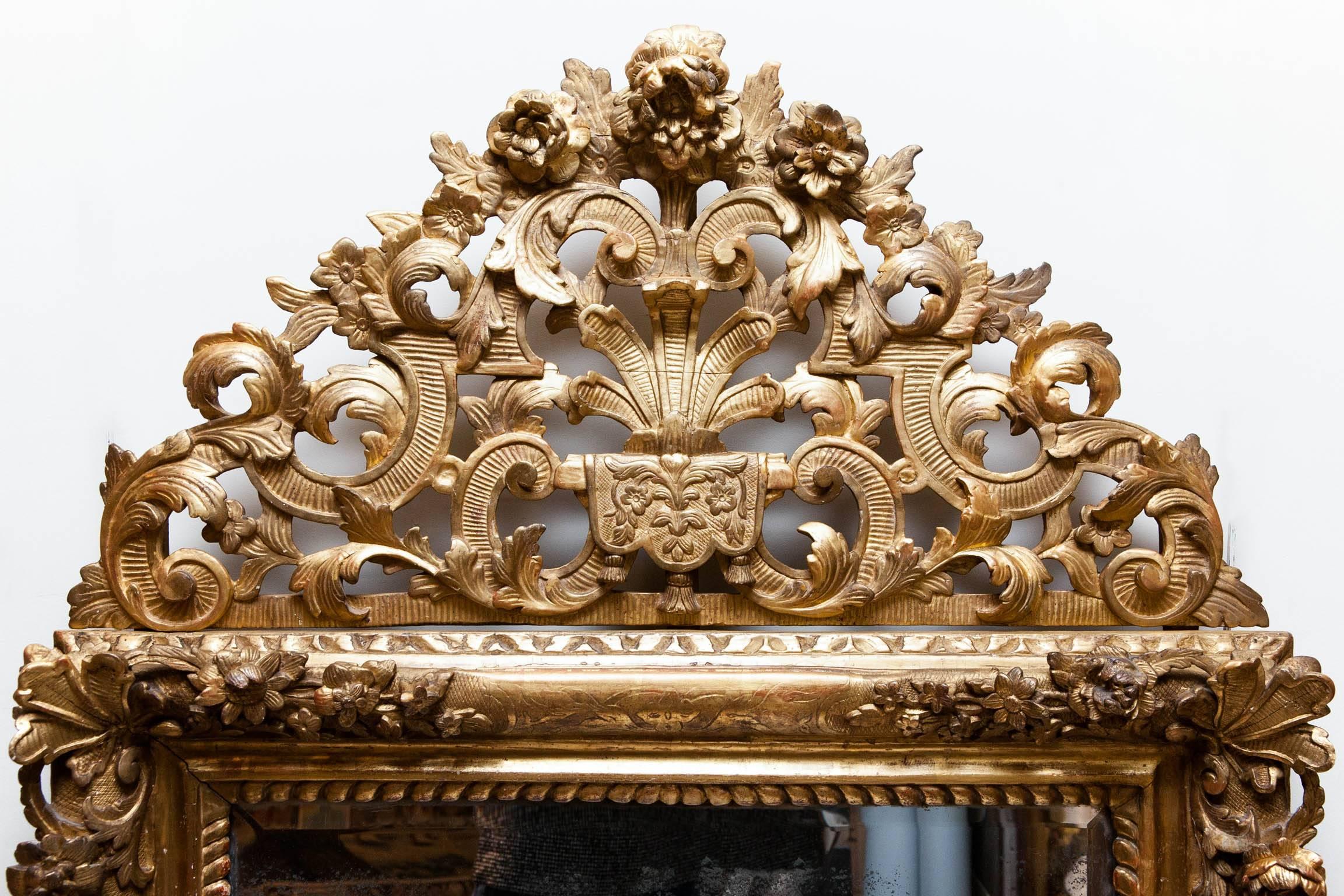 18th century giltwood mirror with detachable top. With carved flowers, garlands and beading to the inner edge of the frame.
Beveled mercury glass plate, France, circa 1750.

We are members of LAPADA and CINOA.