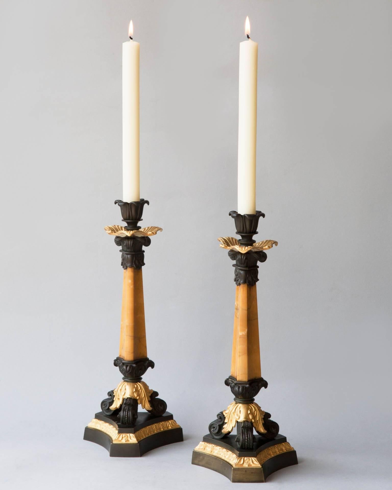 Pair of early 19th century candlesticks, the central pyramid column in Sienna marble, with patinated bronze Corinthian capitol and gilt bronze leaf decoration.
With three scrolling patinated bronze feet and gilt bronze acanthus leaf decoration