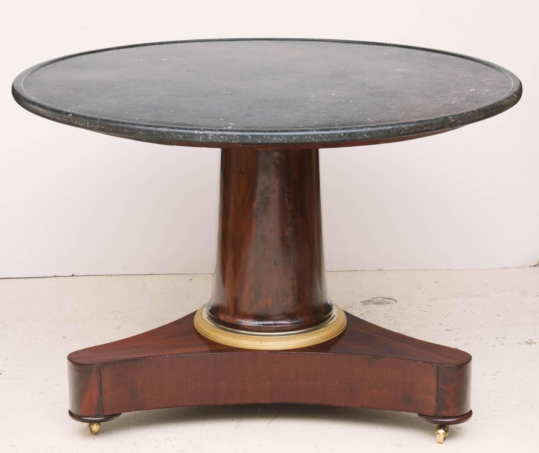 With Belgian black fossil marble top. Central flame mahogany column with gilt bronze ring on tripod base.
Replacement brass castors. Some old repairs to the veneer, see photographs.
France, circa 1810.