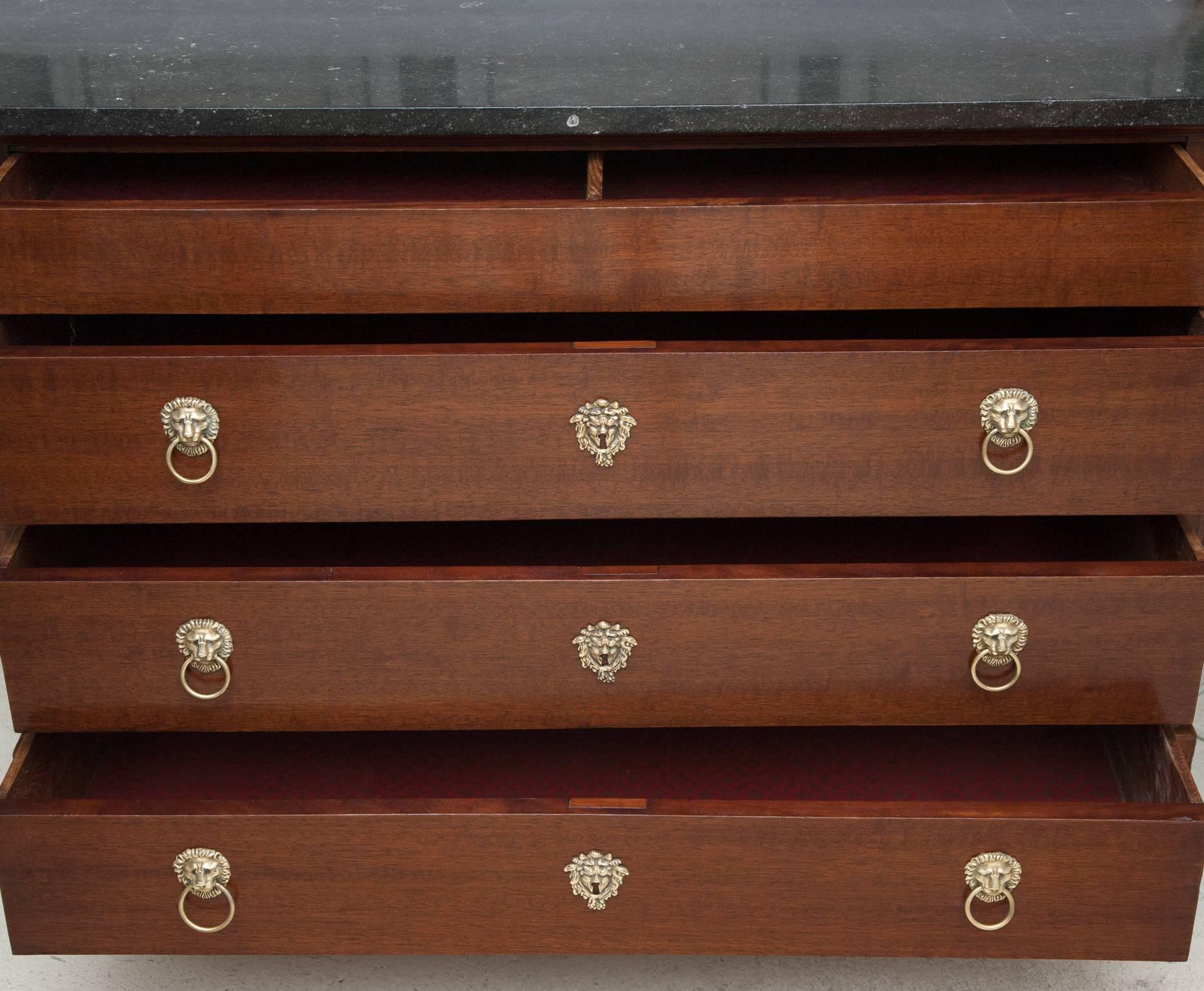 Four long drawers under a Belgian black fossil marble top. The bottom three drawers with brass lion ring pull handles and escutcheons in the form of masks. Supported on two squared legs at the back and ebonized paw feet at the front, 
France, circa