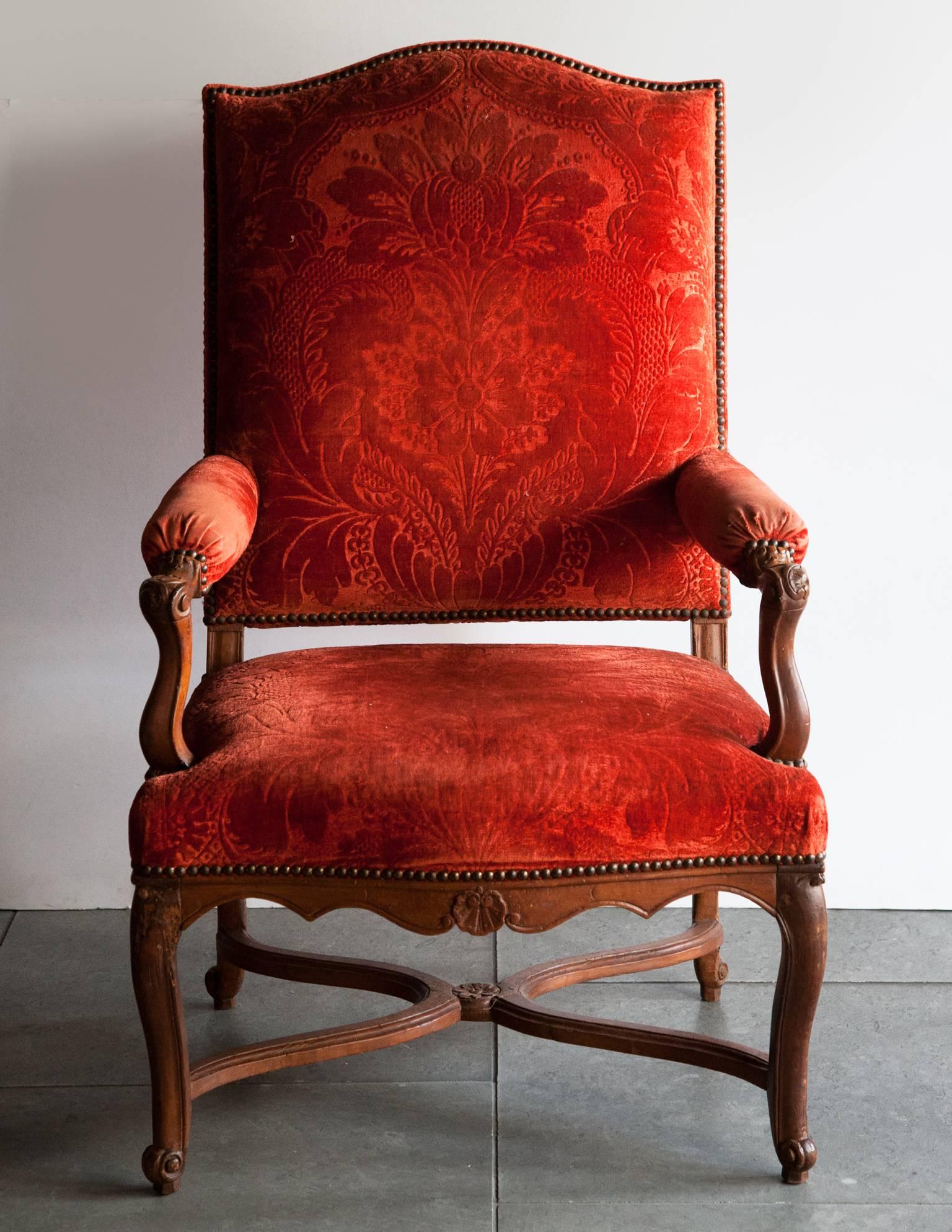 Large Louis XV armchair with carved arms and legs, with a central shell motif on the apron, terminating in scrolling feet. 
Upholstered in later red cut velvet. Traces of old paint on the underneath of the stretcher. 
France, circa 1725.
