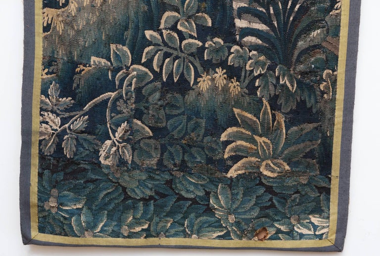 A wooded landscape with a tree in the centre.
Surrounded by a double plain border in dark blue/green and yellow.
Woven in wools and silk, France circa 1720.
The tapestry has old repairs and also has a burn hole at the bottom (see photographs). It