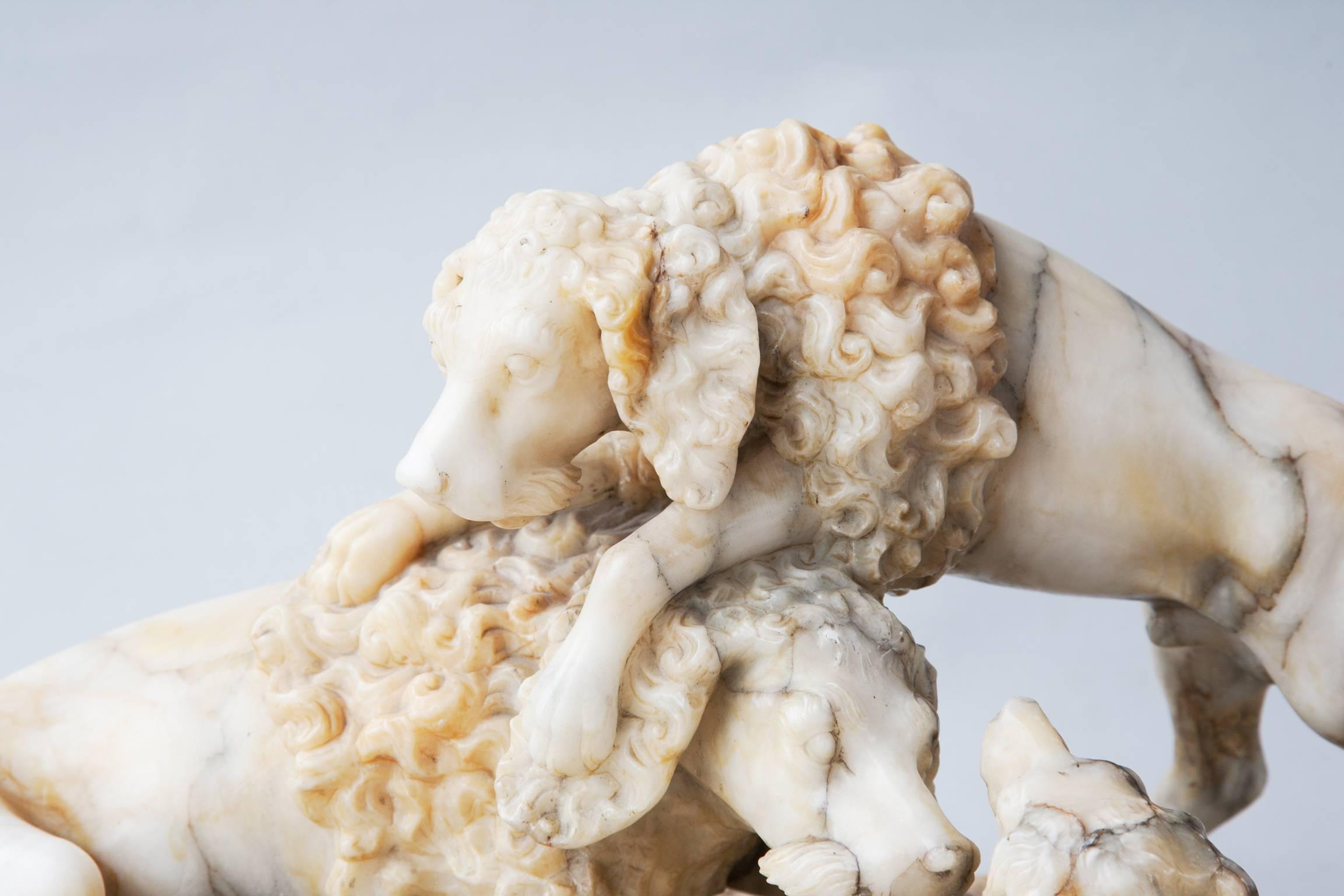 Alabaster sculpture of three dogs. The dogs are remeniscent of French, late 18th-early 19th century paintings of hunting dogs and the curly hair on the shoulders makes them look like working poodles.
    