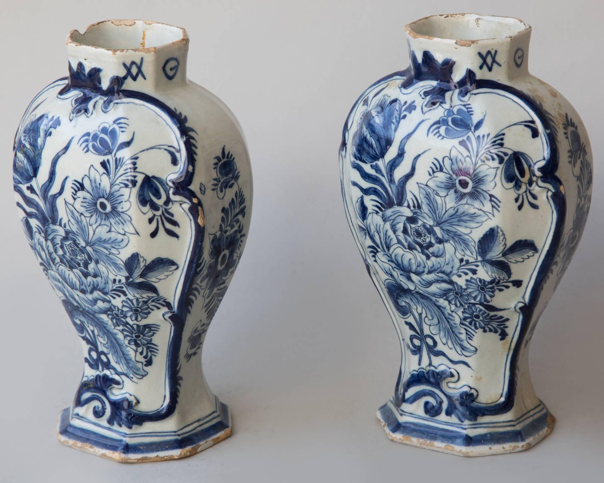 Decorated in blue and white with a Rococo design in relief, with a matching posey of flowers 
to include roses and tulips depicted on each. Stamped by the maker 'PB' on the base. 
The Netherlands, mid-18th century.