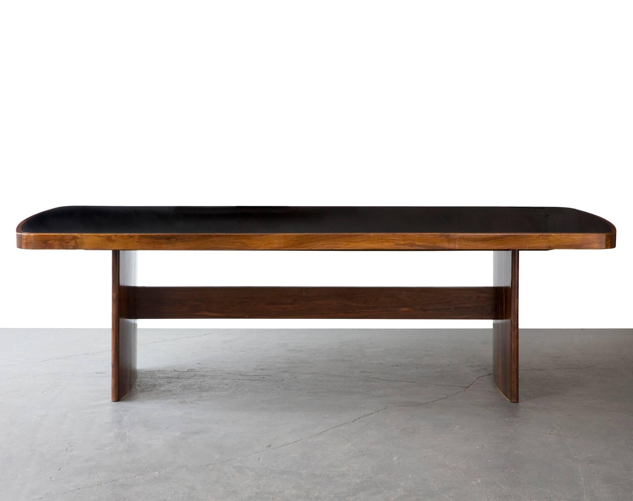 Soft-edged rectangular dining table in jacaranda with black under painted glass top and curved legs. Designed by Joaquim Tenreiro, Brazil, circa 1949.