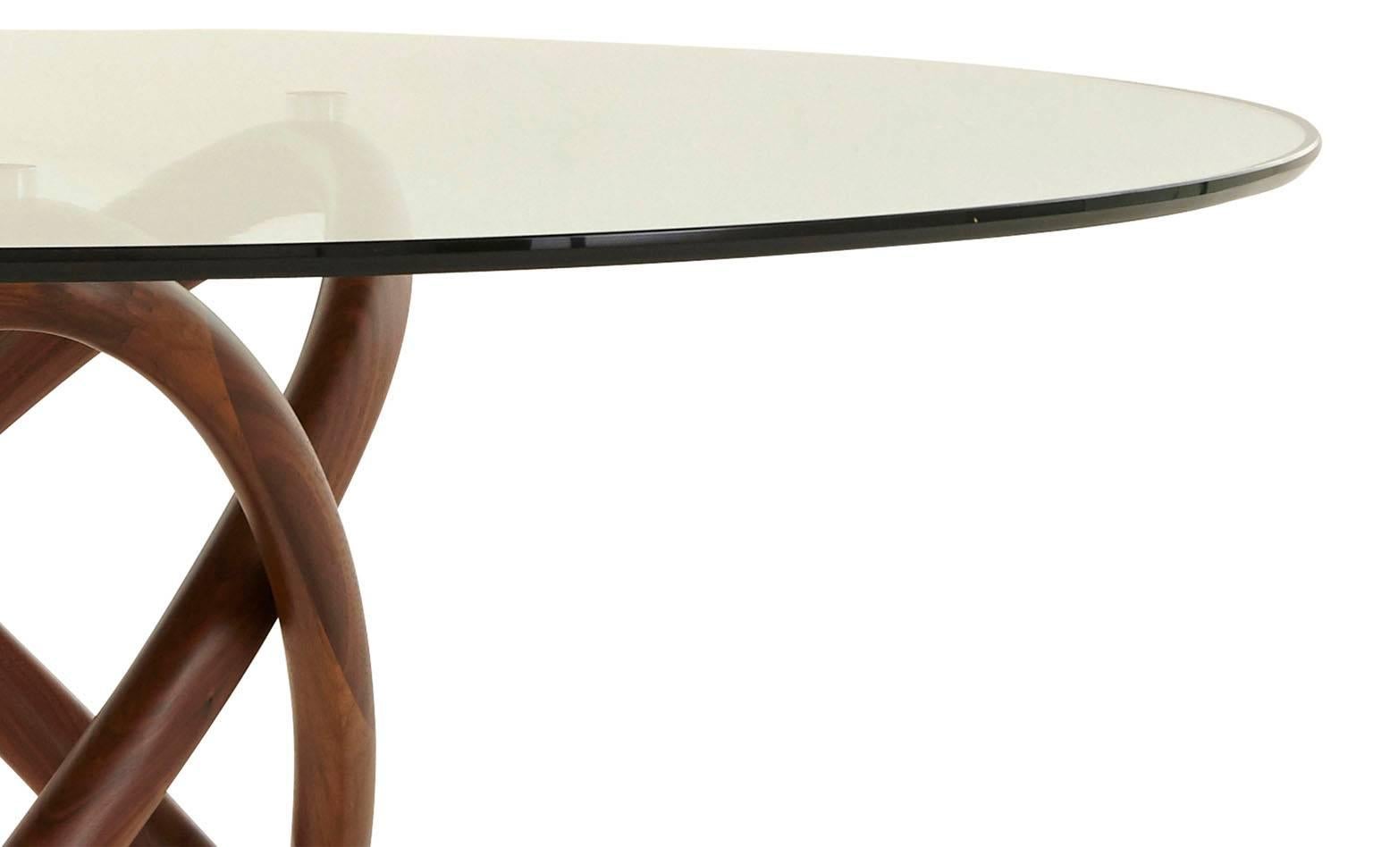 Our Ries table features three elliptical bentwood shapes intertwined to form its unique table base. The rich walnut wood finish is given maximum exposure by the beveled glass tabletop. Pair with our Ries dining chair to mimic the bentwood styling