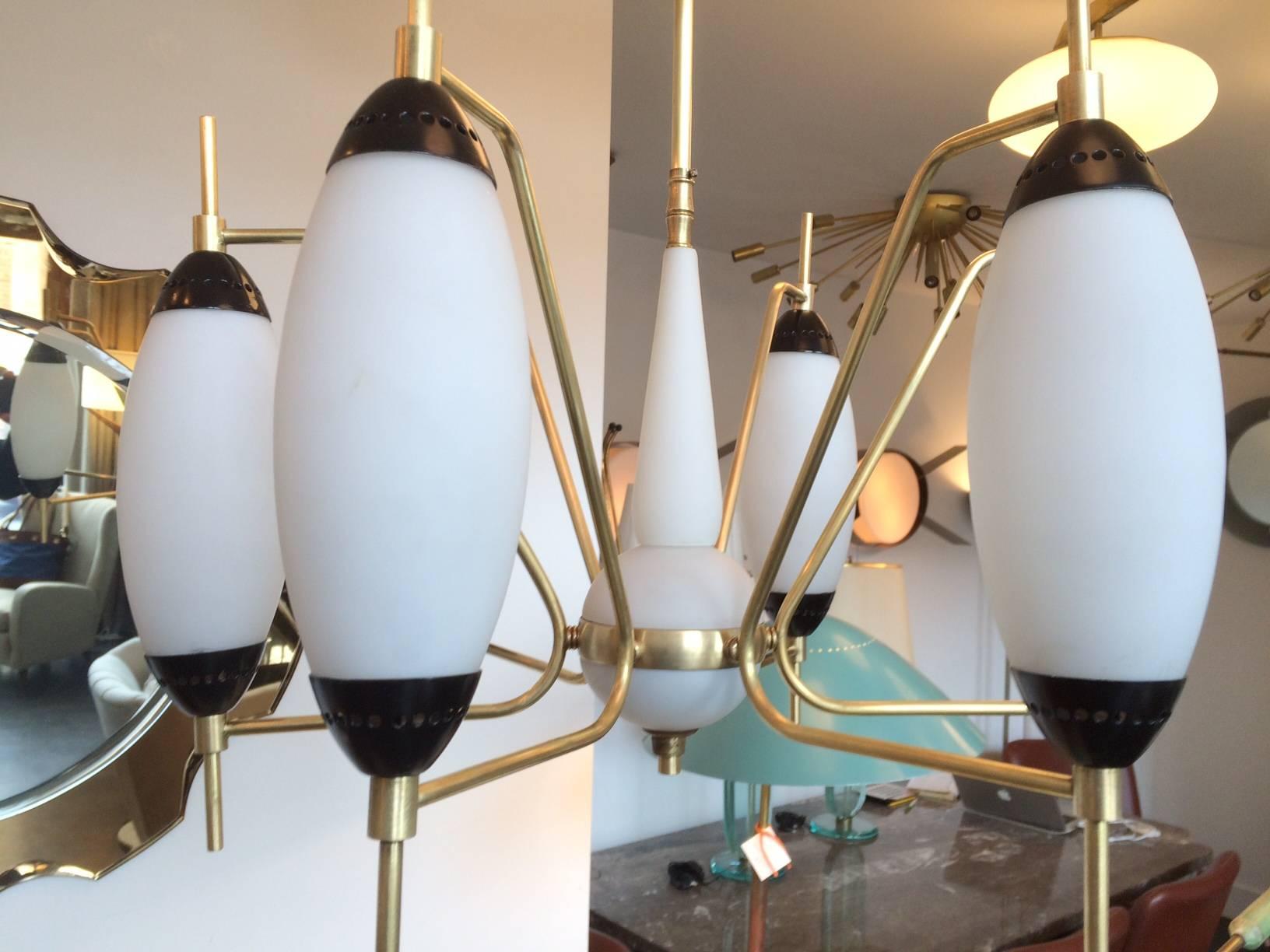 Beautiful brass armatures hold six handblown ellipse shaped white glass shades with black enameled details. Center ball is also white glass and handblown.