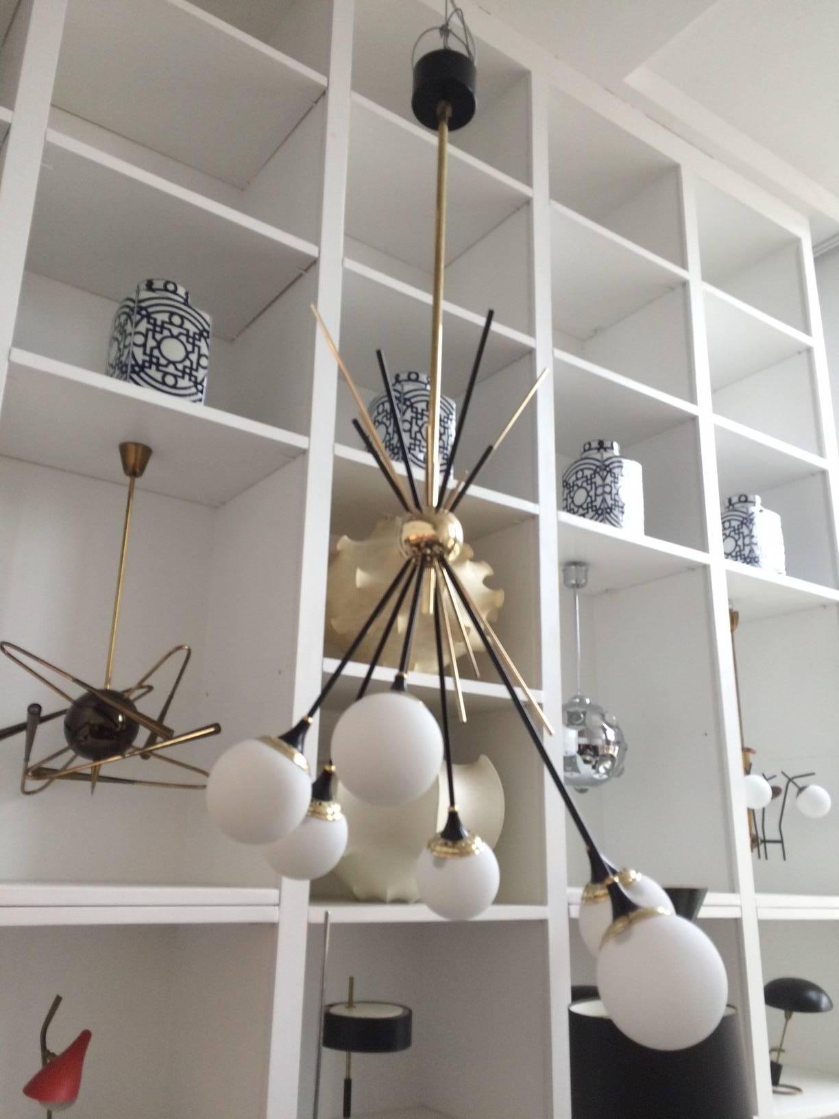 This chandelier has six lights on black enameled stems and six handblown globes that transept the center brass globe clustering the lights in an asymmetric dramatic arrangement.