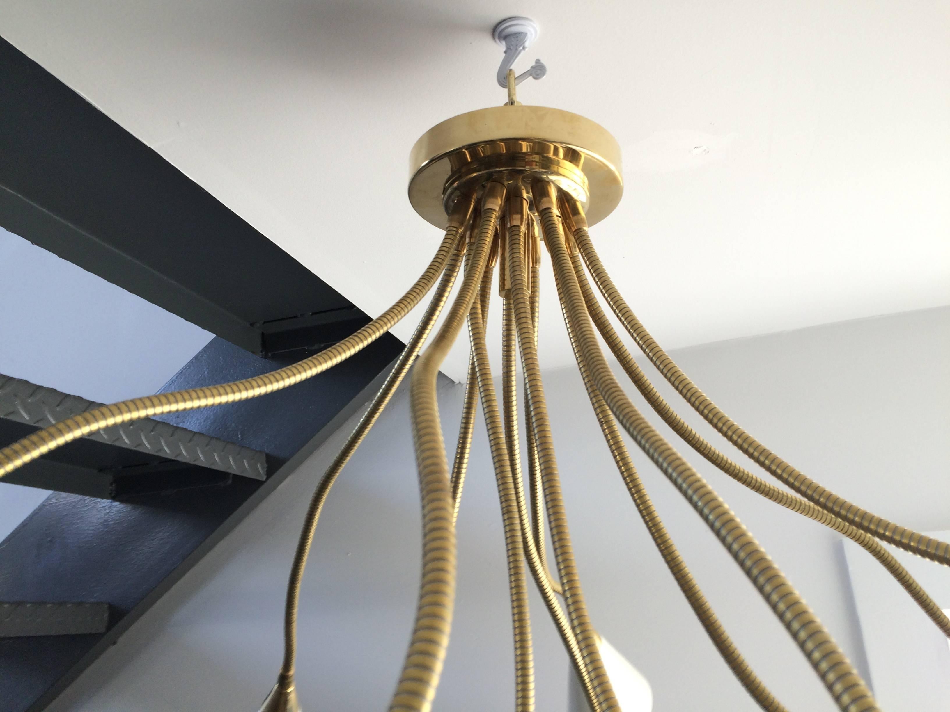 This flush mount brass chandelier has twelve arms or lights
with enameled white aluminium reflectors at the ends
of the flexible brass tubing. Arms radiate from the polished
brass canopy which can be adjusted in any direction.
Arms are fully