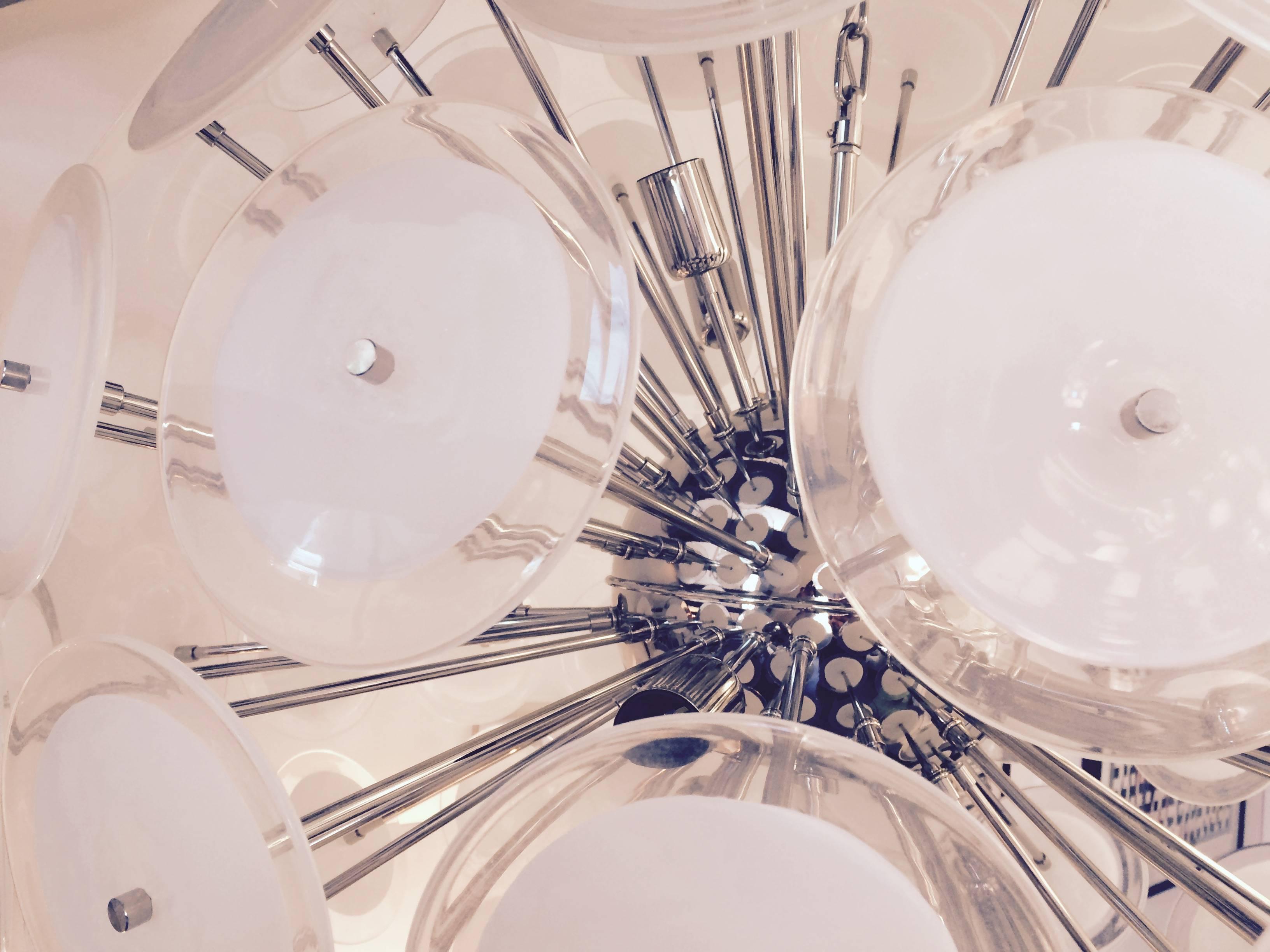 Giant modernist sputnik chandelier created in the 1970's style of Gino Vistosi.  Emanating from the central chrome sphere are  multiple chrome rods with hand blown Murano glass white/clear discs which create a large round flower like form.