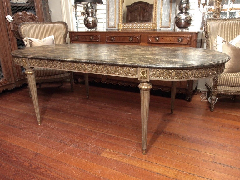 Oval French dining room table with bronze mounted apron raised on fluted tapered legs ending in bronze caps. Faux finish marble top.