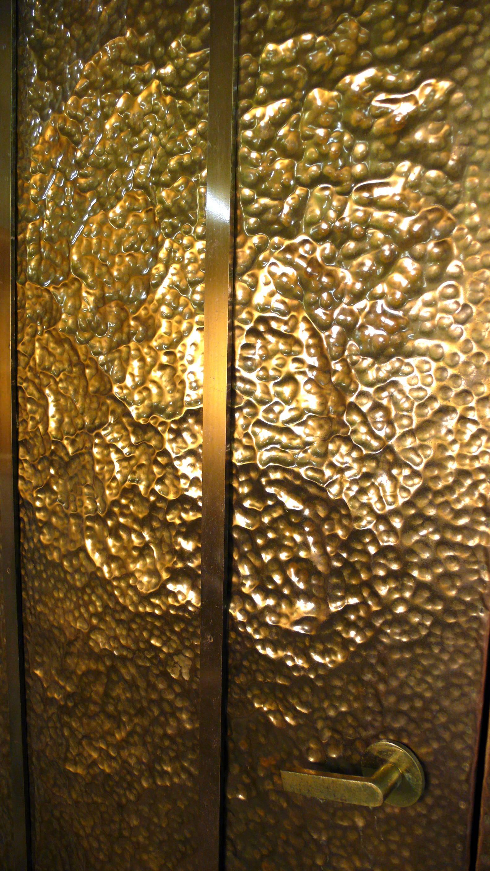 This pair of custom, hand-hammered brass doors were salvaged from an incredible Mid-Century Modern home here in Texas. One side of each door is clad in brass with solid, flat-bar brass detailing and brass handles. The other side is a Philippine