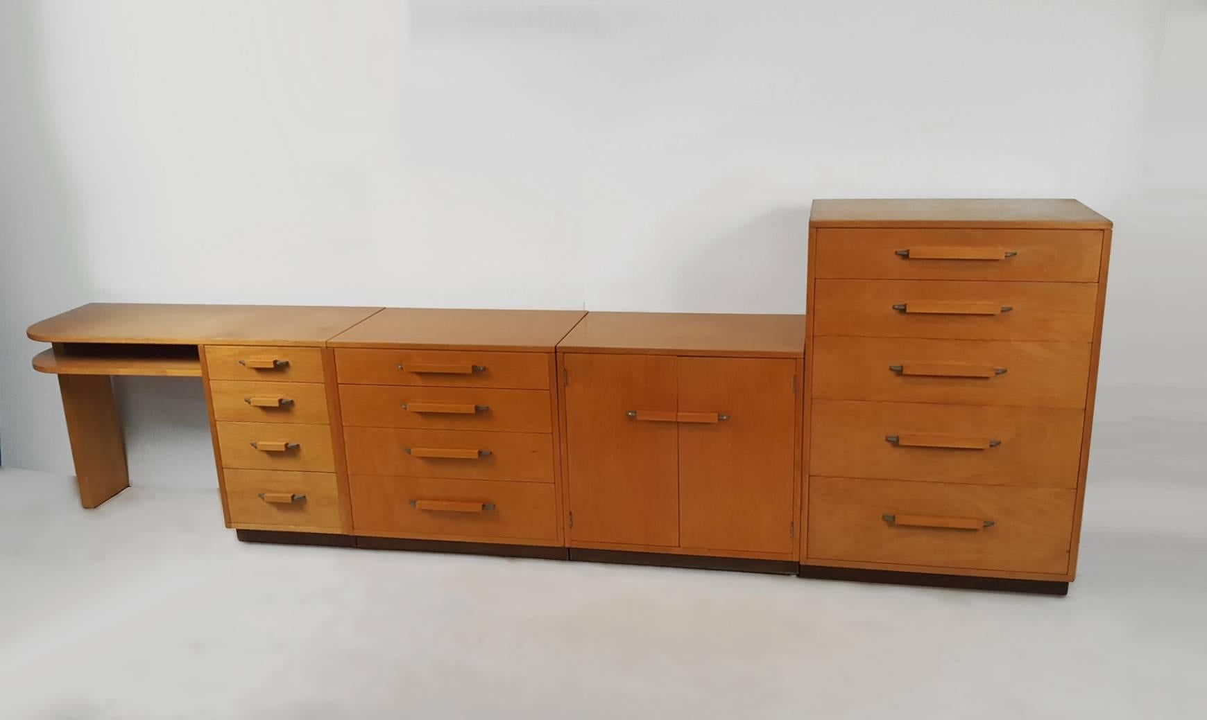 A collection of five different components from the 'Flexible Home Arrangement' collection designed by architect Eliel Saarinen in collaboration with his daughter for Johnson Furniture Company. Includes a desk, two chests of drawers, a cabinet with