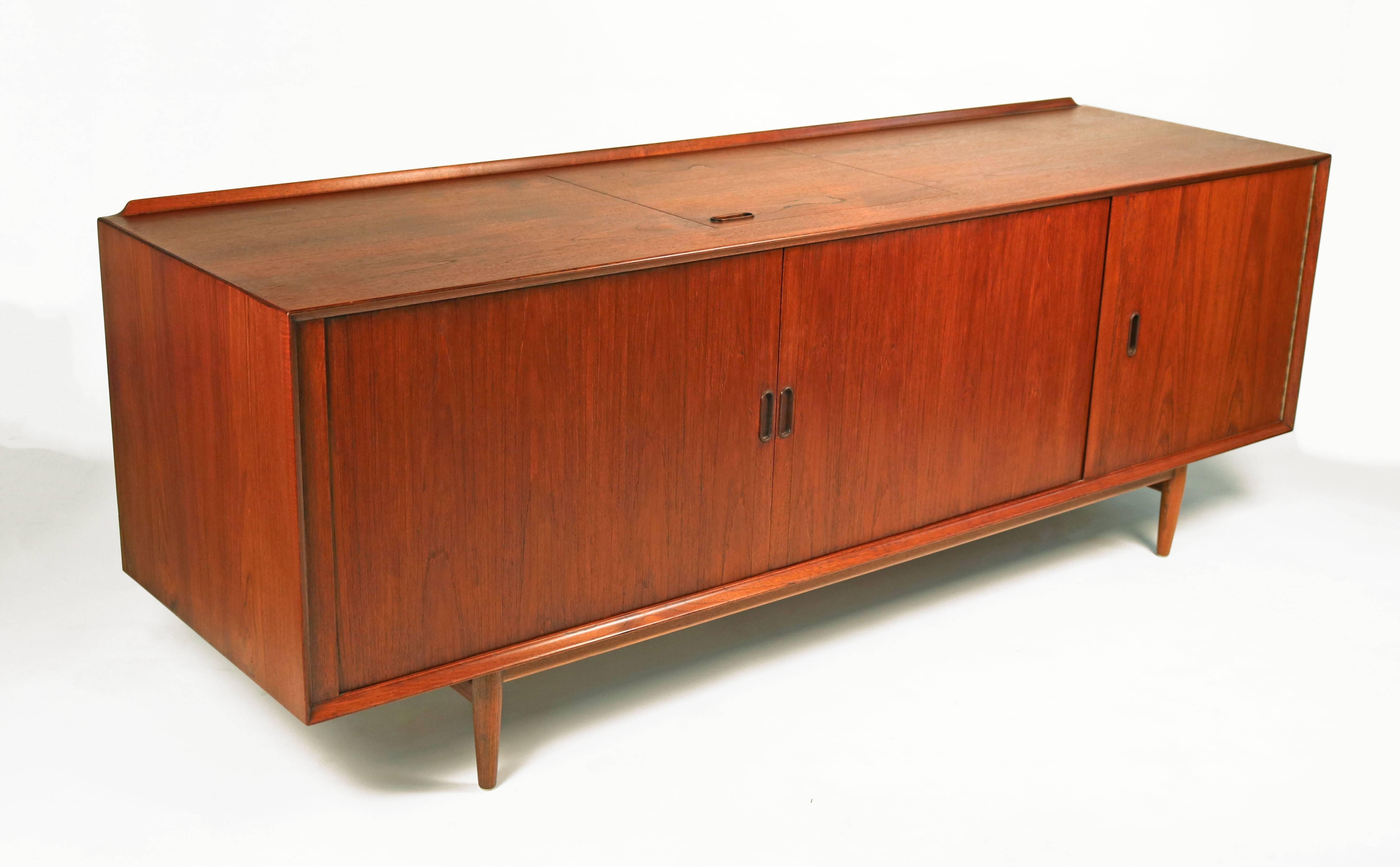 Teak wood Scandinavian Modern stereo or media cabinet. The unit consists of two beautiful book-matched tambour doors and a flip-top hatch which was designed to provide easy turn table access. Many compartments for storage and stereo or television