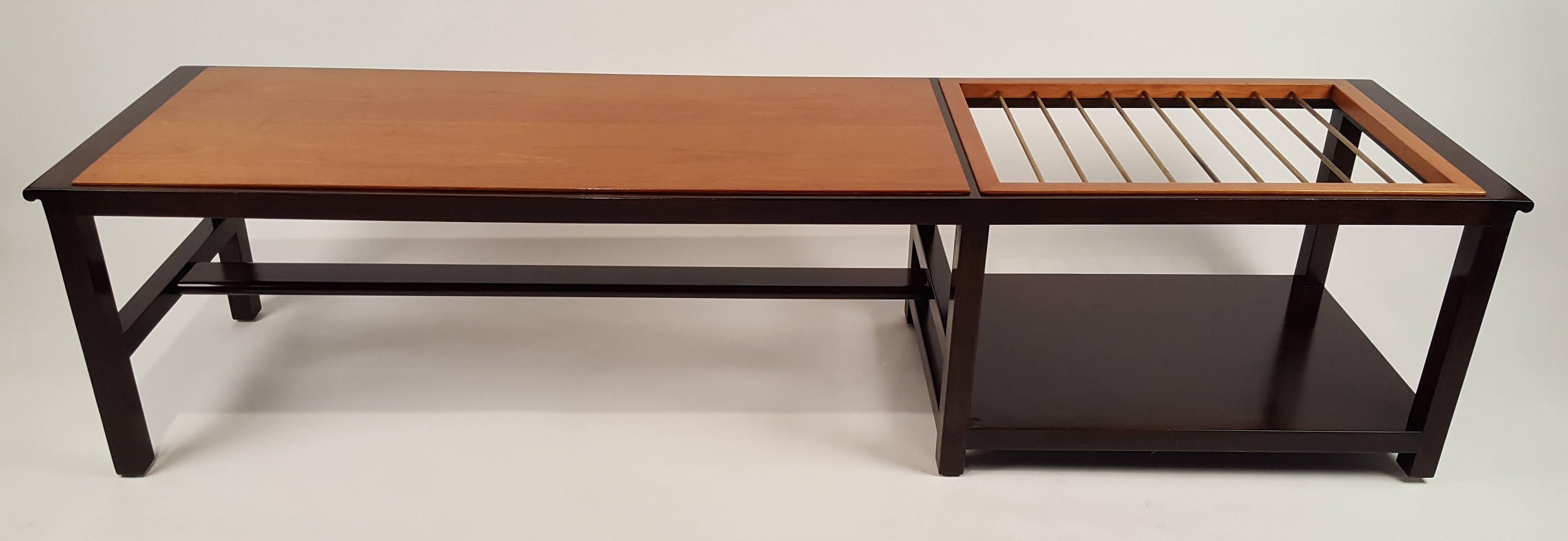 An exceptional Dunbar coffee table or bench (Model 5933a) with built-in brass rods for suspending magazines. Another option would be to recess a glass top over the rods to use as a surface for beverages. The rim and base are constructed of solid