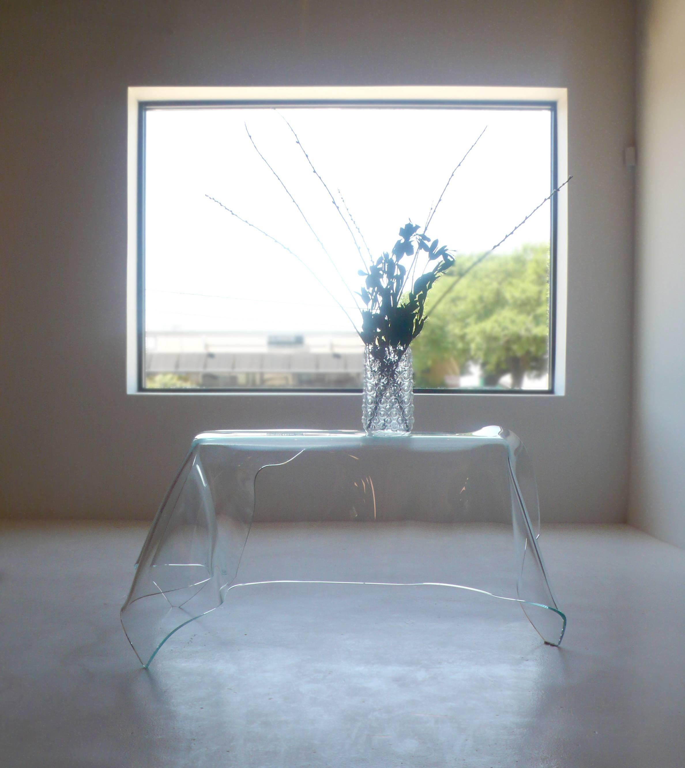 This is an absolutely breathtaking piece. It is impossible to capture the beauty and simplicity of this desk with a camera. It is a thick clear sheet of glass that has been manipulated by the world renowned glass artist Laurel Fyfe into the form of