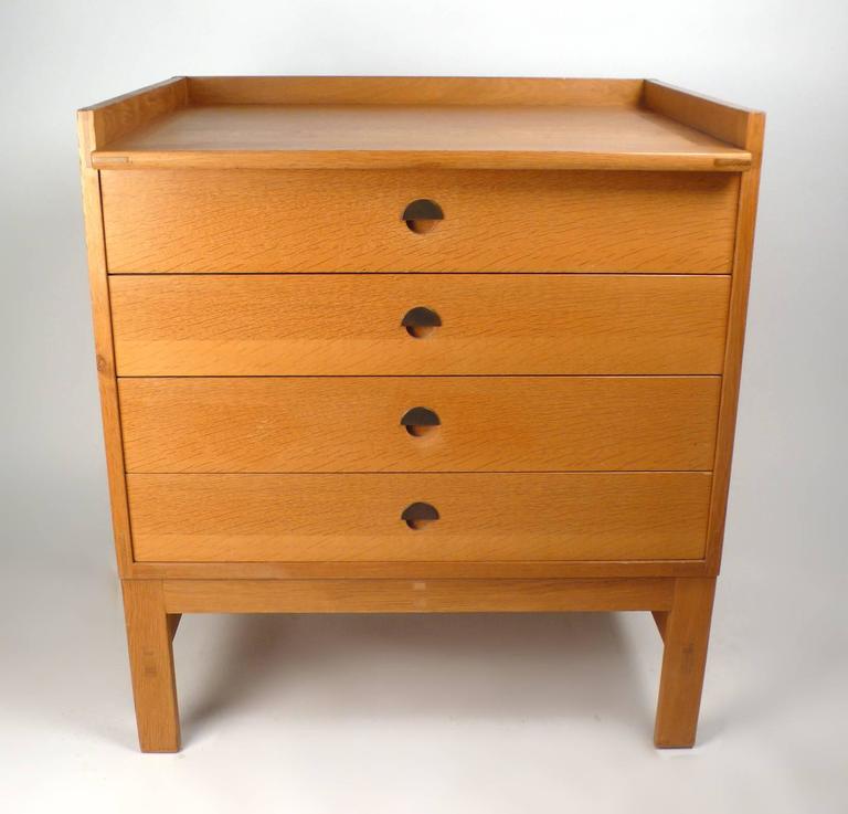 A fine and rare Danish Modern oak chest of drawers designed by Ilse Rix for Uldum Møbelfabrik. This cabinet is a combination of quarter-sawn oak and rift cut oak with inset bronze semicircular hardware. The craftsmanship of this piece is exquisite.