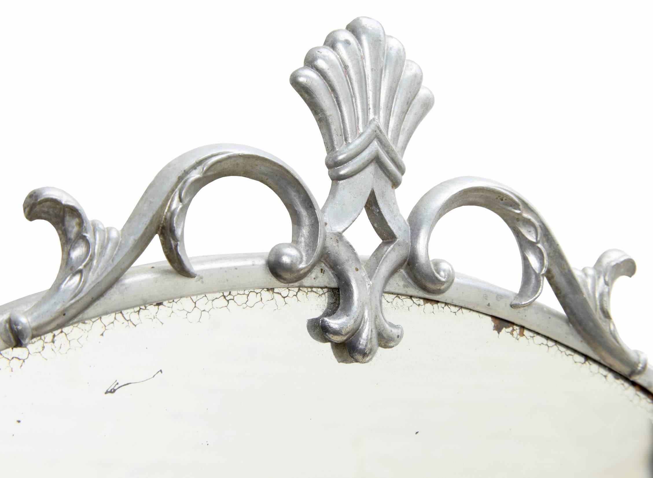 Two Art Deco pewter mirrors, circa 1940. Pair of mirrors, one surmounted by an Archer and other by feather and swags. Some marks to plate.

Height: 19 1/4