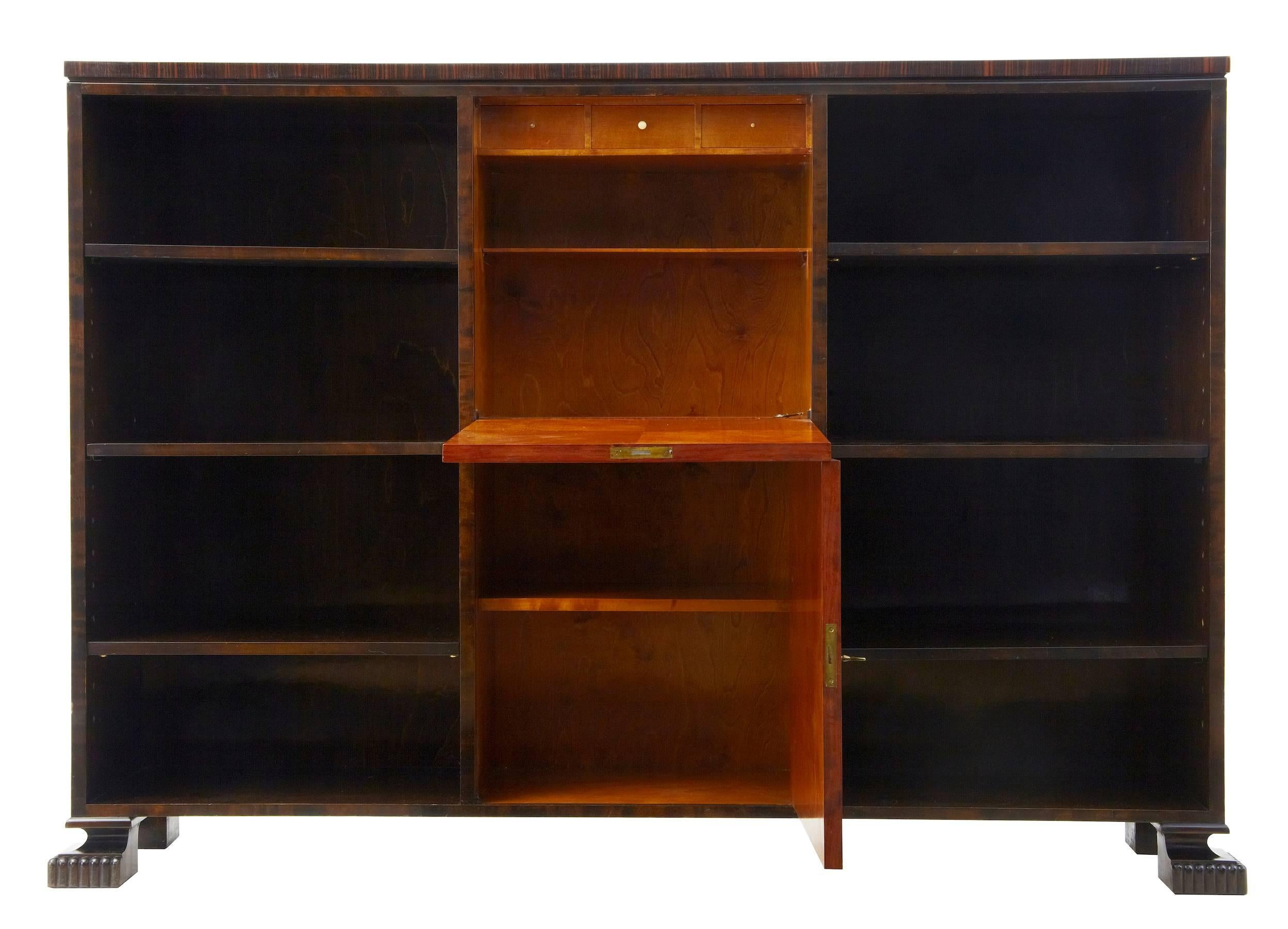 Early 20th century Art Deco open bookcase cabinet
Fine quality bookcase or cabinet in birch and rosewood, circa 1920.
Central inlaid drop down door to reveal a semi fitted interior of drawers and single shelf, below which a cupboard with single
