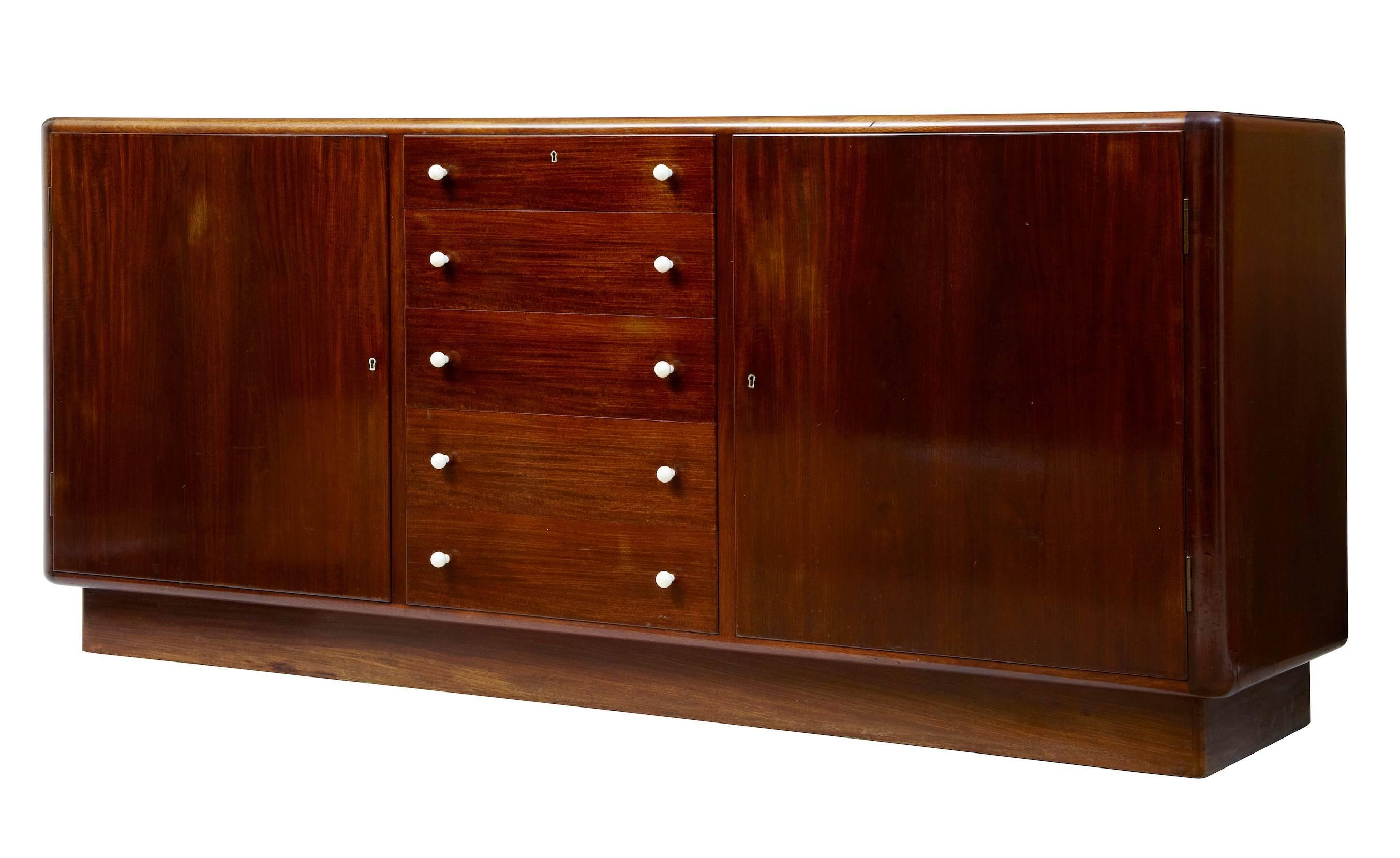 Large, 1950s Danish Mahogany Sideboard
Good quality Danish sideboard, circa 1950.
Curved form edges with white plastic knobs.
A bank of five drawers, two of which are felt lined for cutlery are flanked either side by a single door cupboard. Two