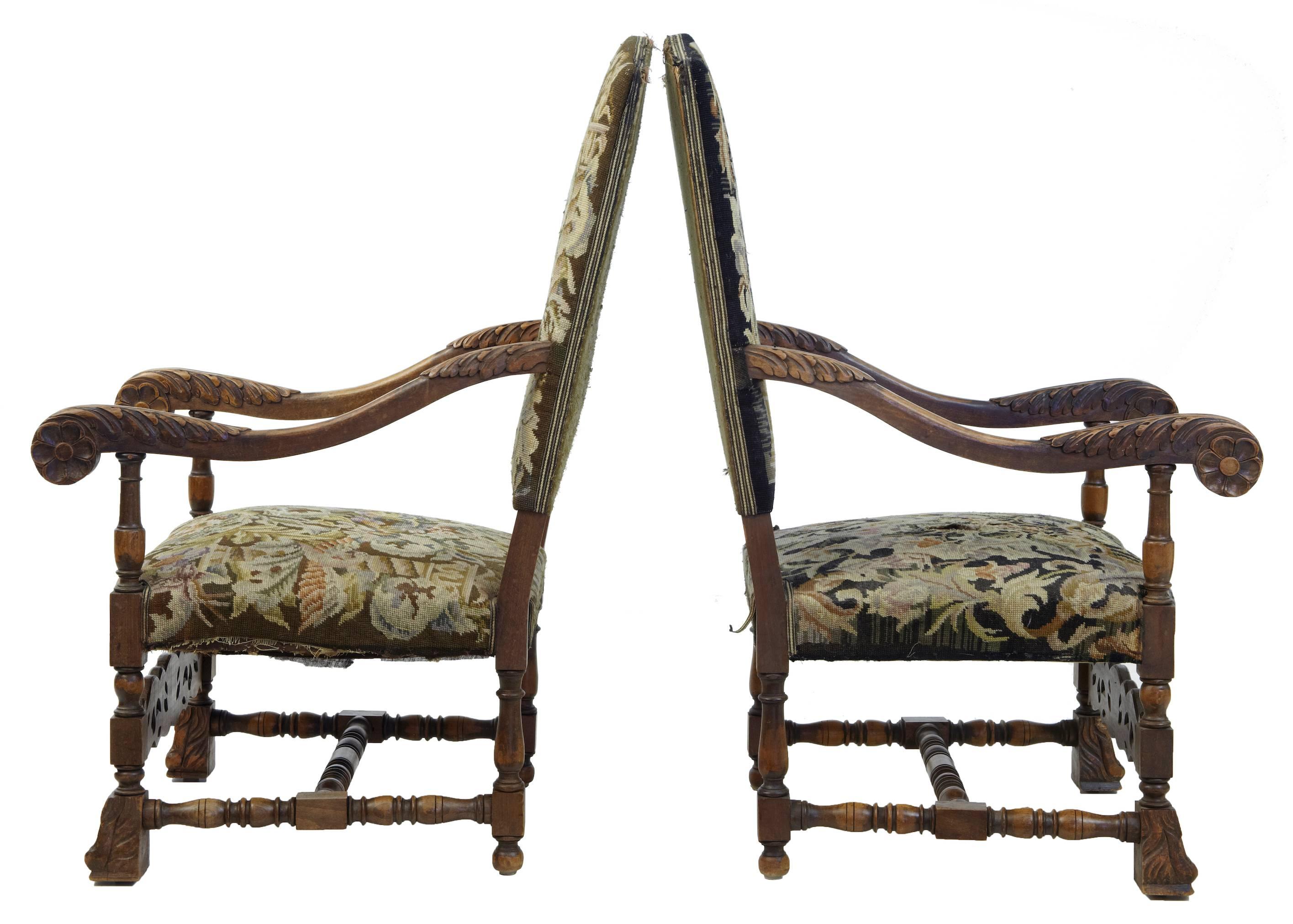 Pair of carved oak armchairs with original upholstery circa 1880.
Scrolling arms with carved acanthus leaves.
Block paw feet, united by h frame stretcher.
Contrasting fabrics on each chair, some wear and holes to covering.  (see