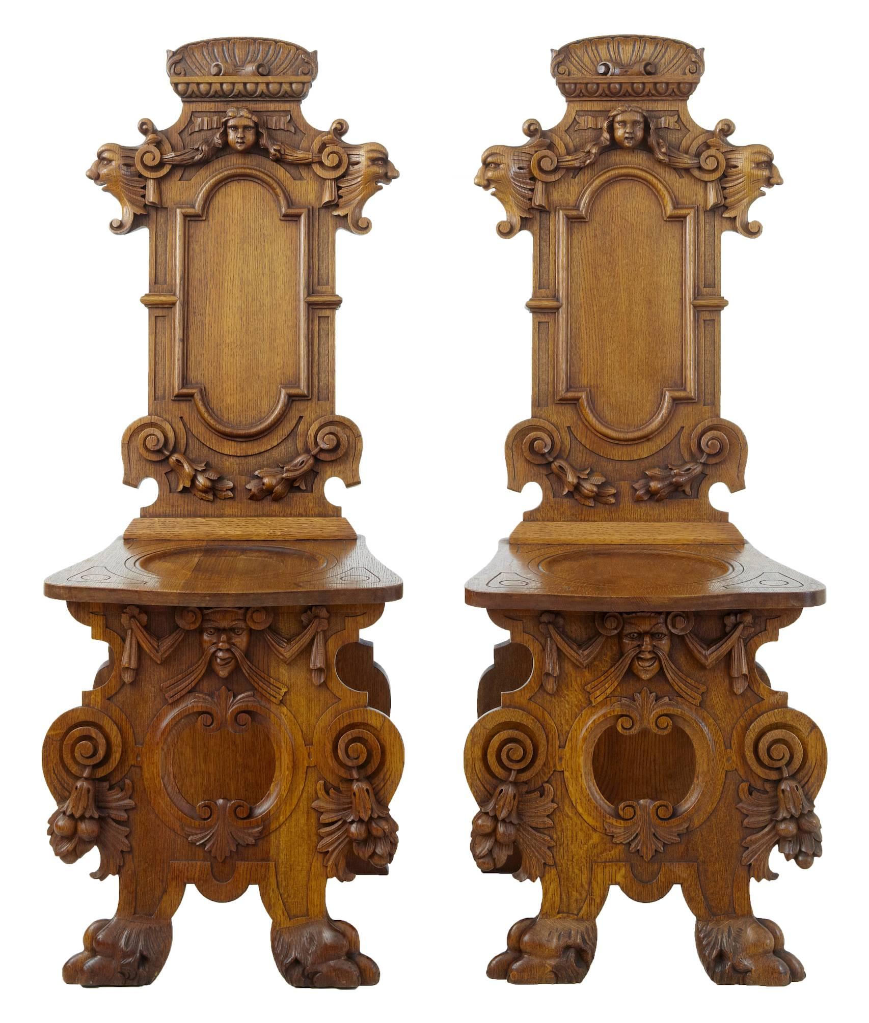 Pair of Flemish carved golden oak hall chairs, circa 1890.
Profusely carved with heads, swags and foliage.
Dished seat.
Nice rich golden oak color

Height: 46 1/2