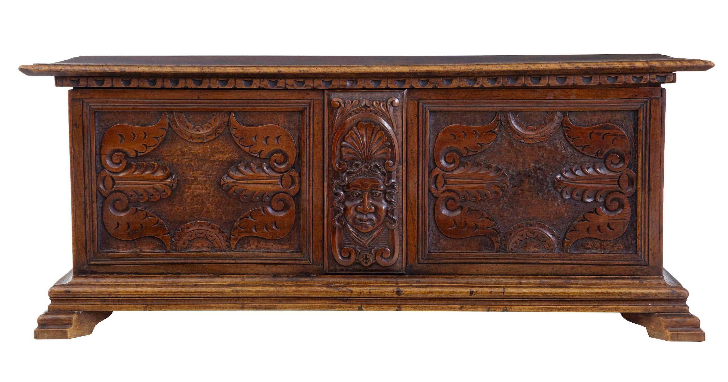 19th century Flemish walnut coffer, circa 1870.
Baroque influenced carving featuring a tribal face to the front.
Lid opens to plain interior.

Measures: Height 20 1/2".
Width 51".
Depth 20".