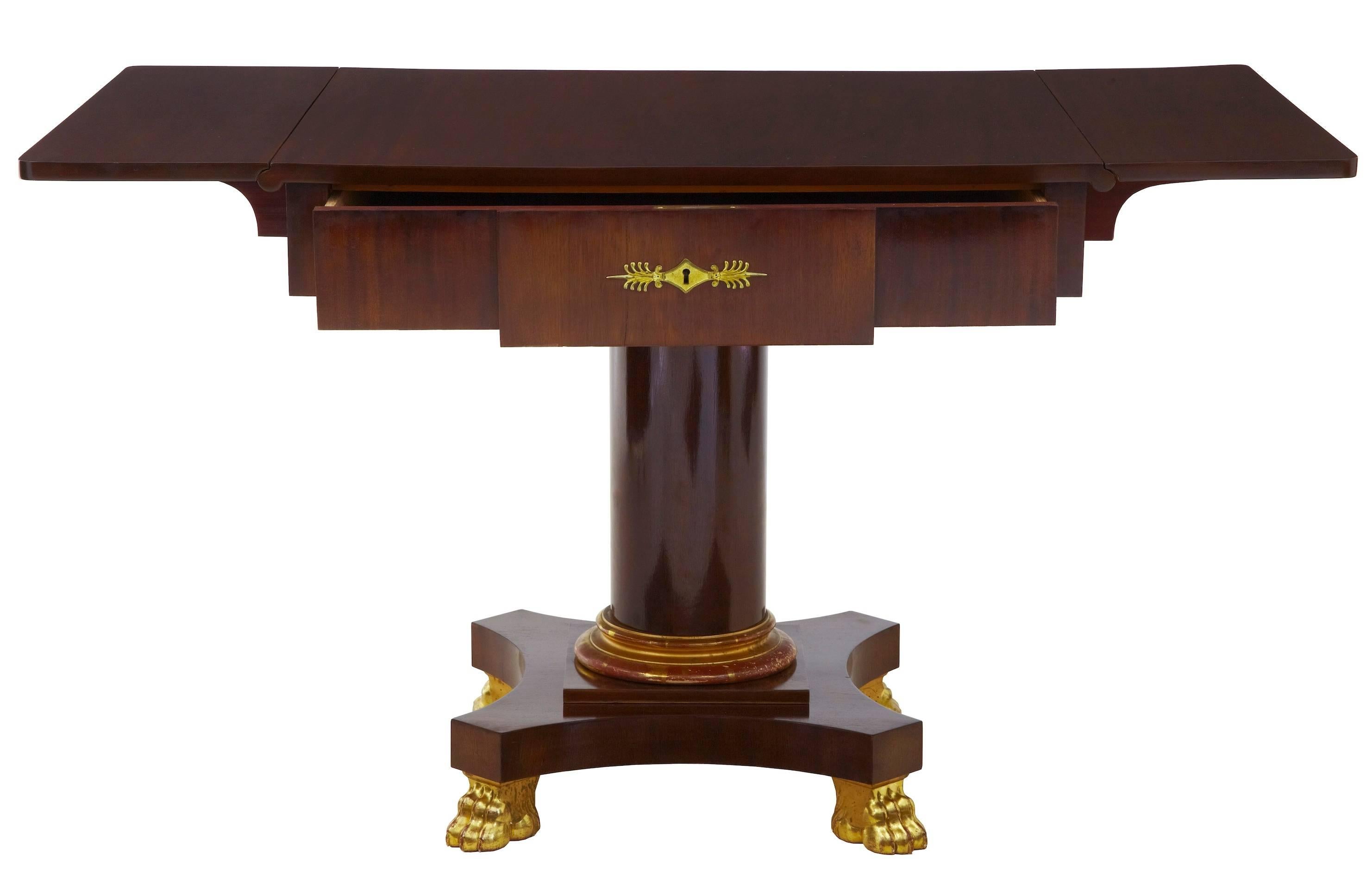 Good quality mahogany sofa table, strong in Empire design, circa 1910.
Single drawer to the front.
Barrel stem, standing on four gilt carved paw feet.
No key.
Measures:
Height: 30 1/4