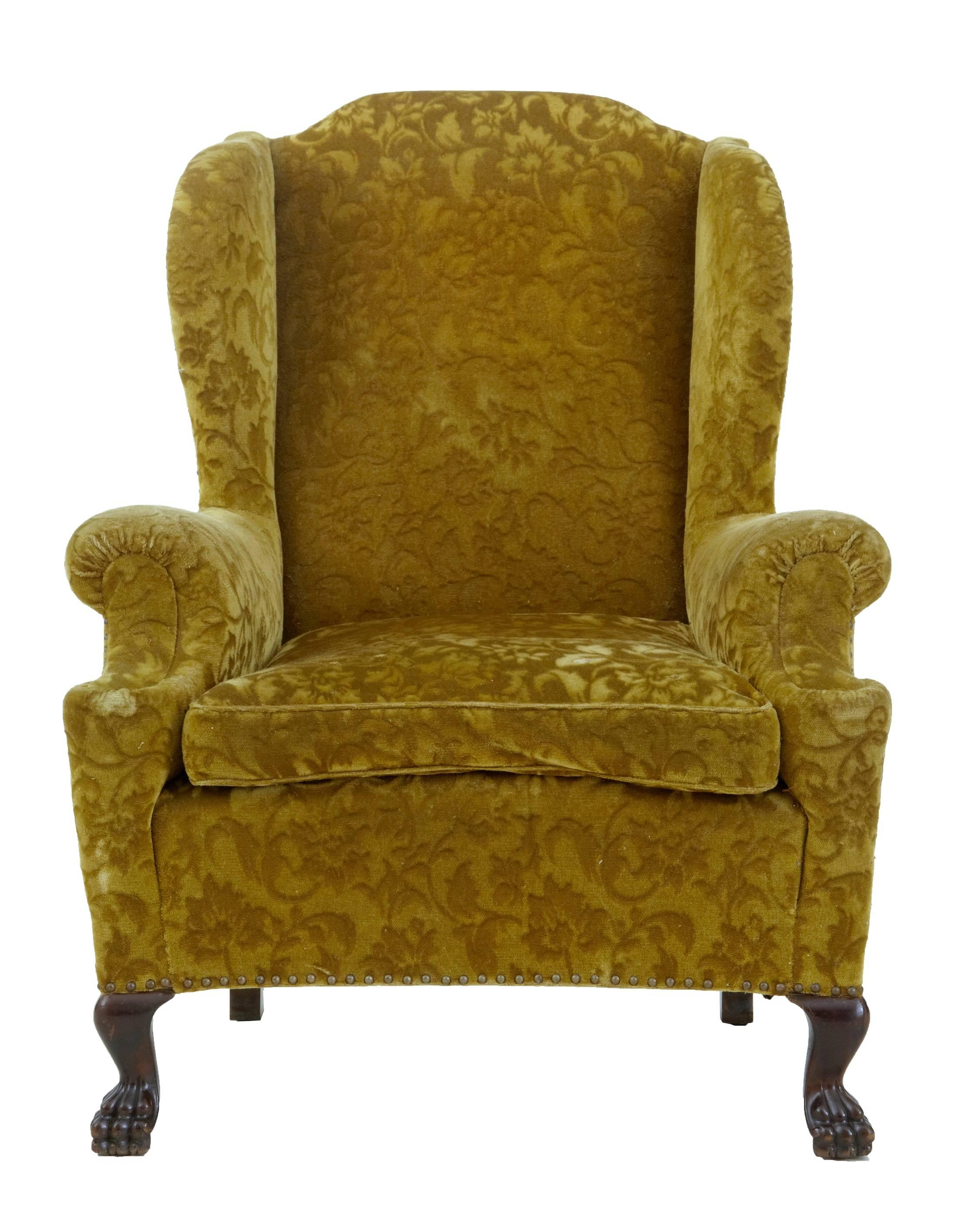 Very comfortable wingback armchair, circa 1920.
Carved paw feet to the front.
Concave shaped front.

Crushed green velvet does have the odd mark and stain, but this chair is worthy of being recovered, but perfectly usable as it