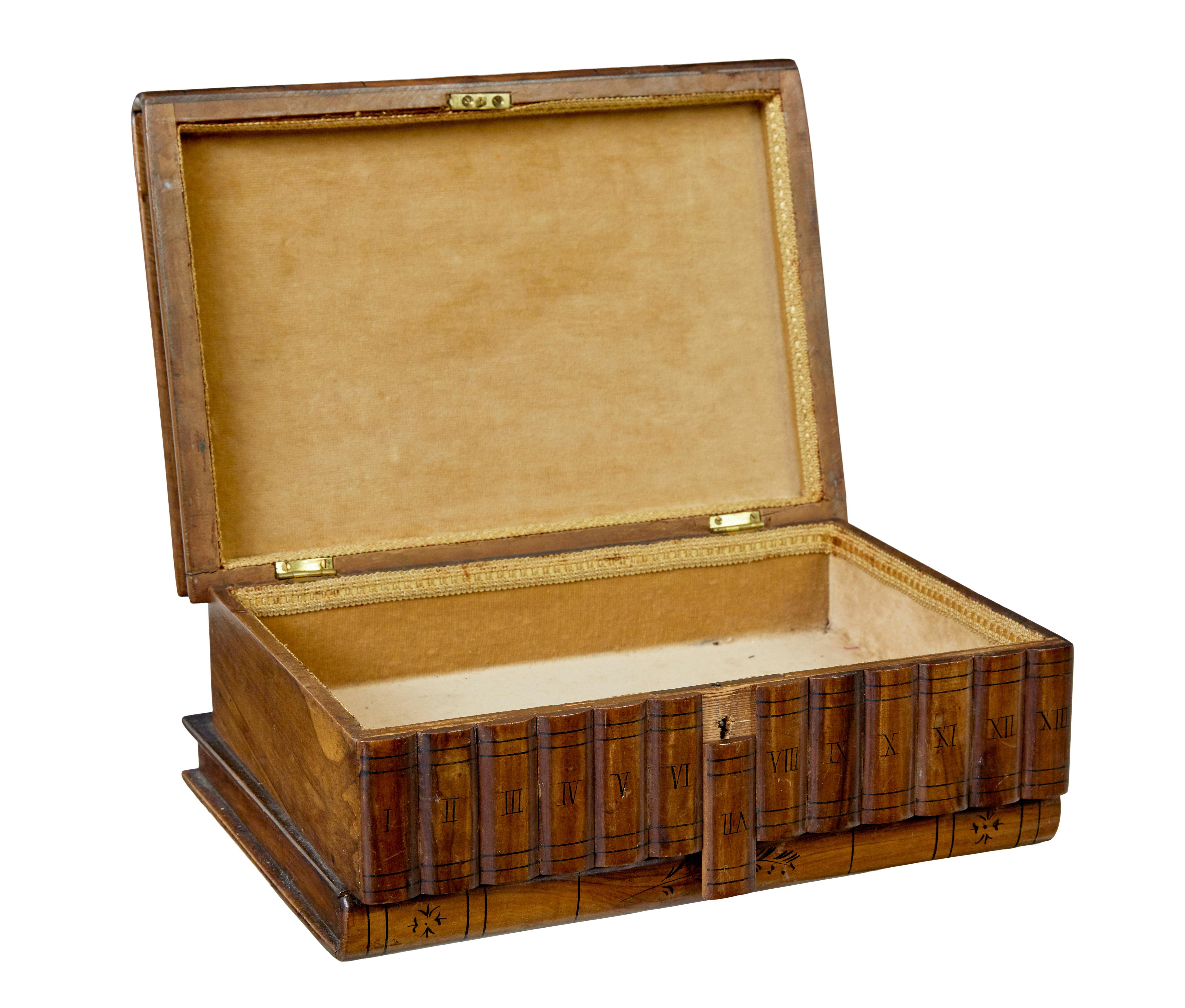 19th century book shaped inlaid olive box circa 1890.

Unusual Italian keep sake box made in olive wood.  Inlaid top surface with musical instrument, flowers and a faux peeled back corner, finished in a mosaic border.  Front of the box with hand