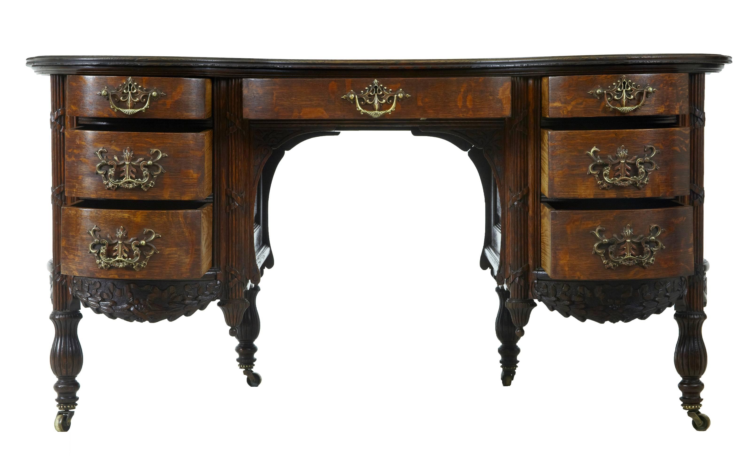 Carved oak kidney shaped desk, circa 1895.
Oak writing surface with burr, below which a central drawer over the knee hole, complimented either side by graduating drawers with ornate brass handles.
Standing on four fluted legs with brass