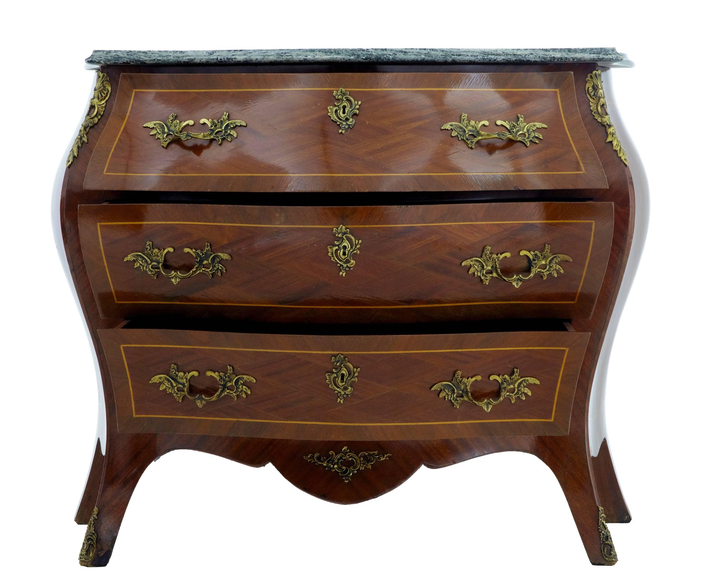 Good quality bombe shape commode, circa 1950.
Three drawers with ornate handles.
Inlaid and crossbanded with kingwood and mahogany, strung with satinwood.
Marble-top.
Some veneer losses to feet and marks to side.

Measures: Height: 31