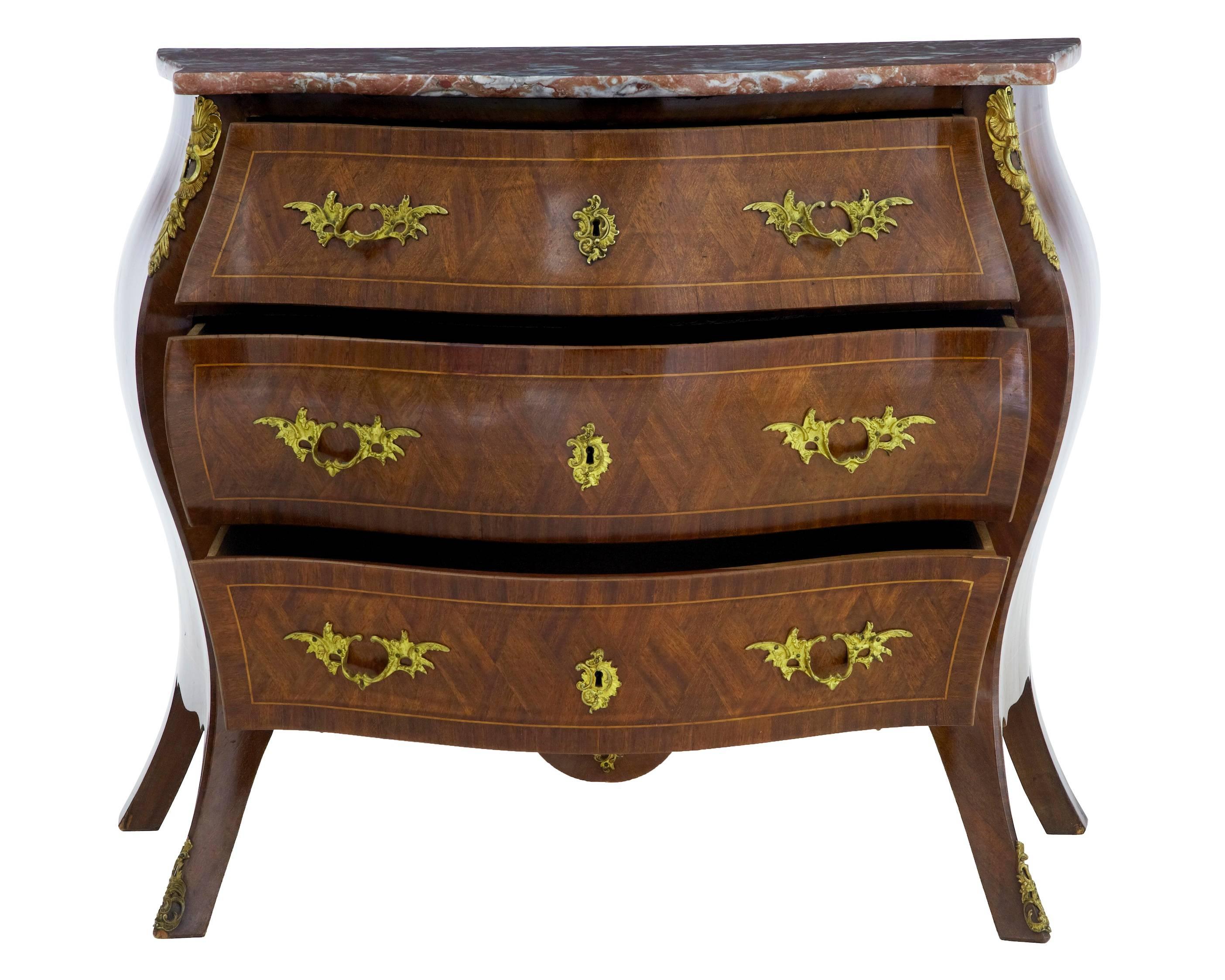 Good quality bombe shape commode, circa 1950.
Three drawers with ornate handles.
Inlaid and crossbanded with kingwood and mahogany, strung with satinwood.
Marble-top.
Oak lined drawers.
Minor marks to side.
 