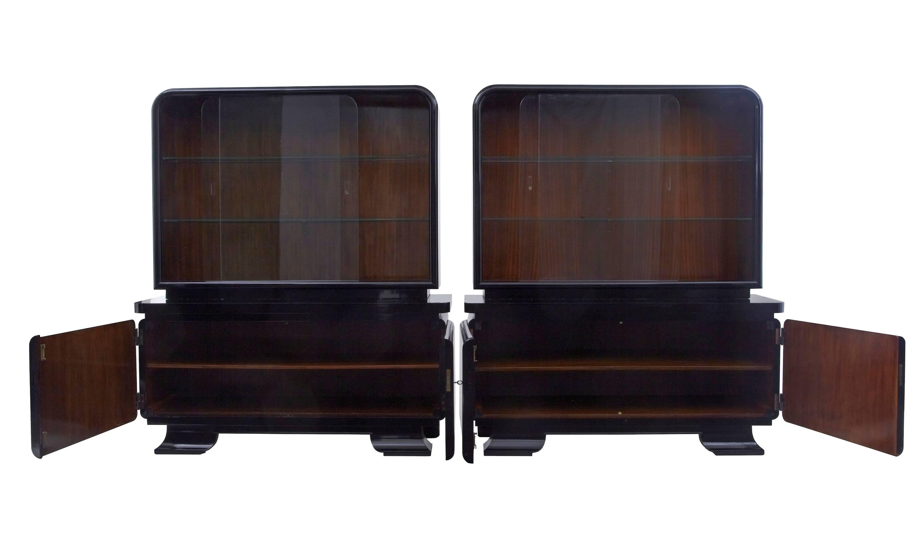 Debenham antiques are proud to offer a premium pair of stylish Art Deco cabinet / vitrines, circa 1930.
Comprising of two parts.
Finished in black lacquer with contrasting wood interiors.
Top section with glass doors and two glass