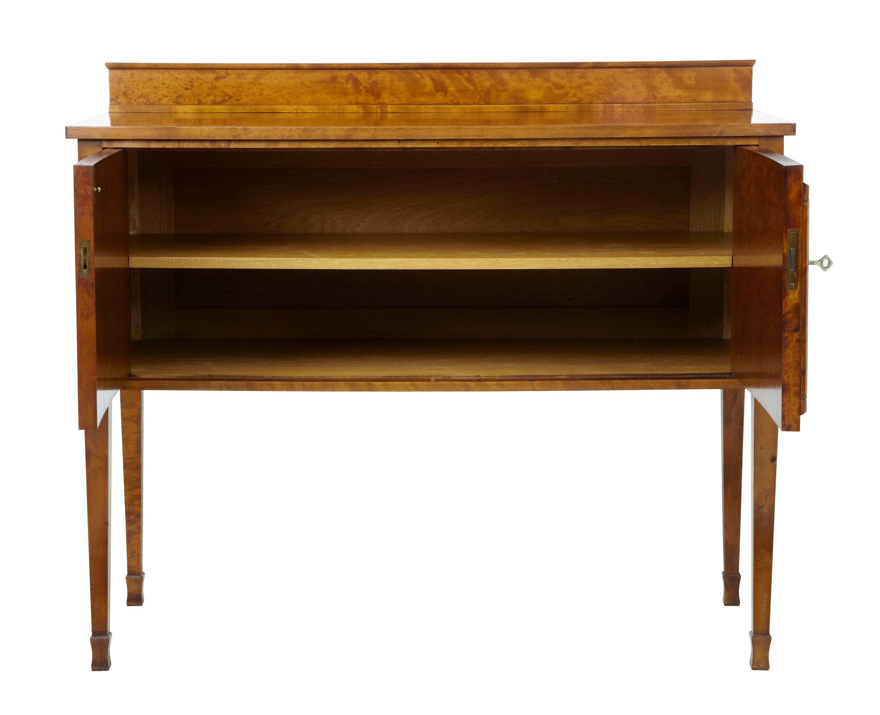 Art Deco period birch sideboard, circa 1930.
Top with small gallery back.
Double doors open to reveal a single full width shelf.
Carved roundel details to door fronts.

Measures: Height 36 3/4