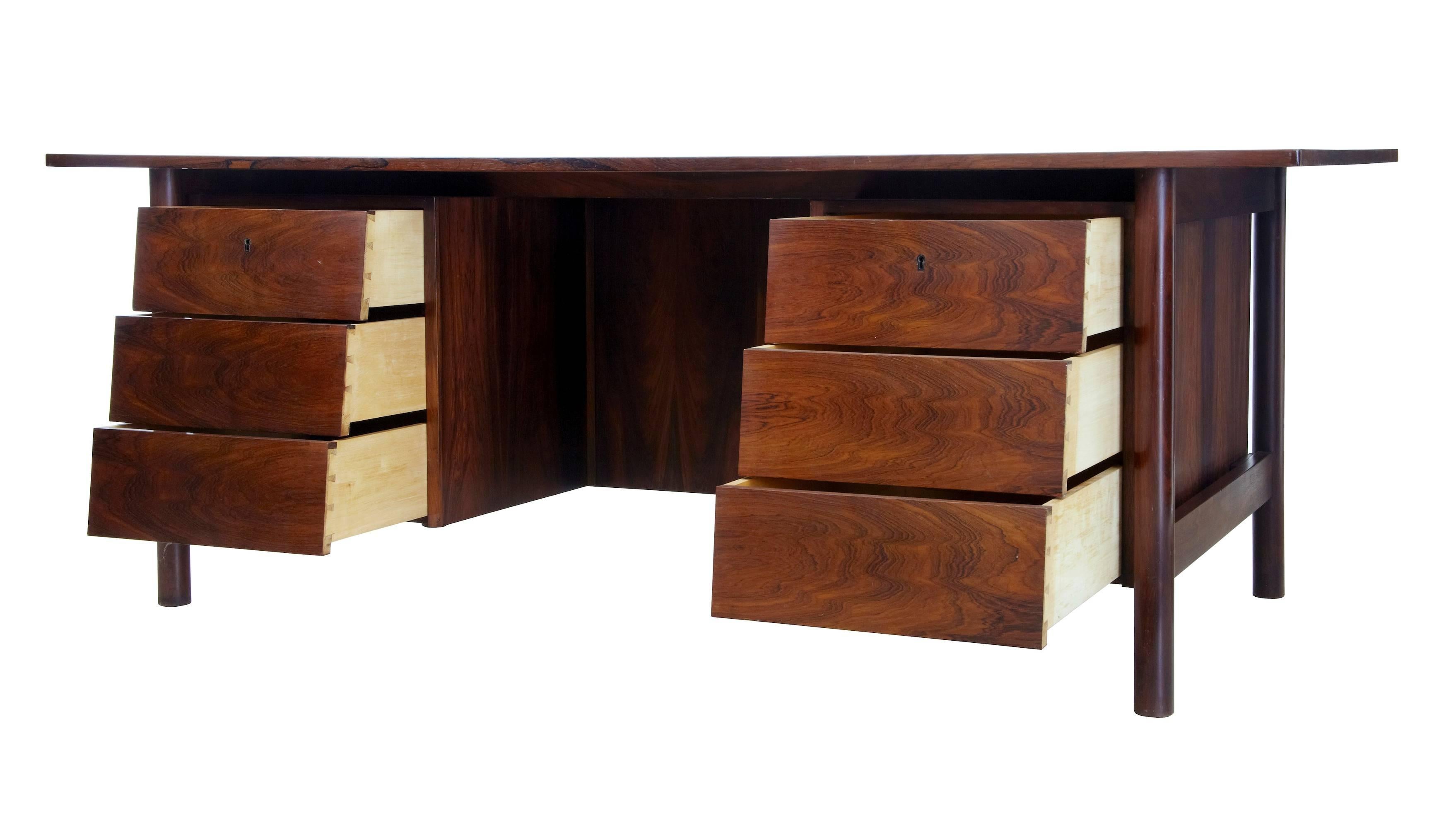 Excellent quality freestanding jacaranda rosewood desk, circa 1960.
Oversailing striking rosewood top.
Two banks of stepped drawers either side of the knee hole, on the reverse is a single shelf bookcase.
There is further storage space above the