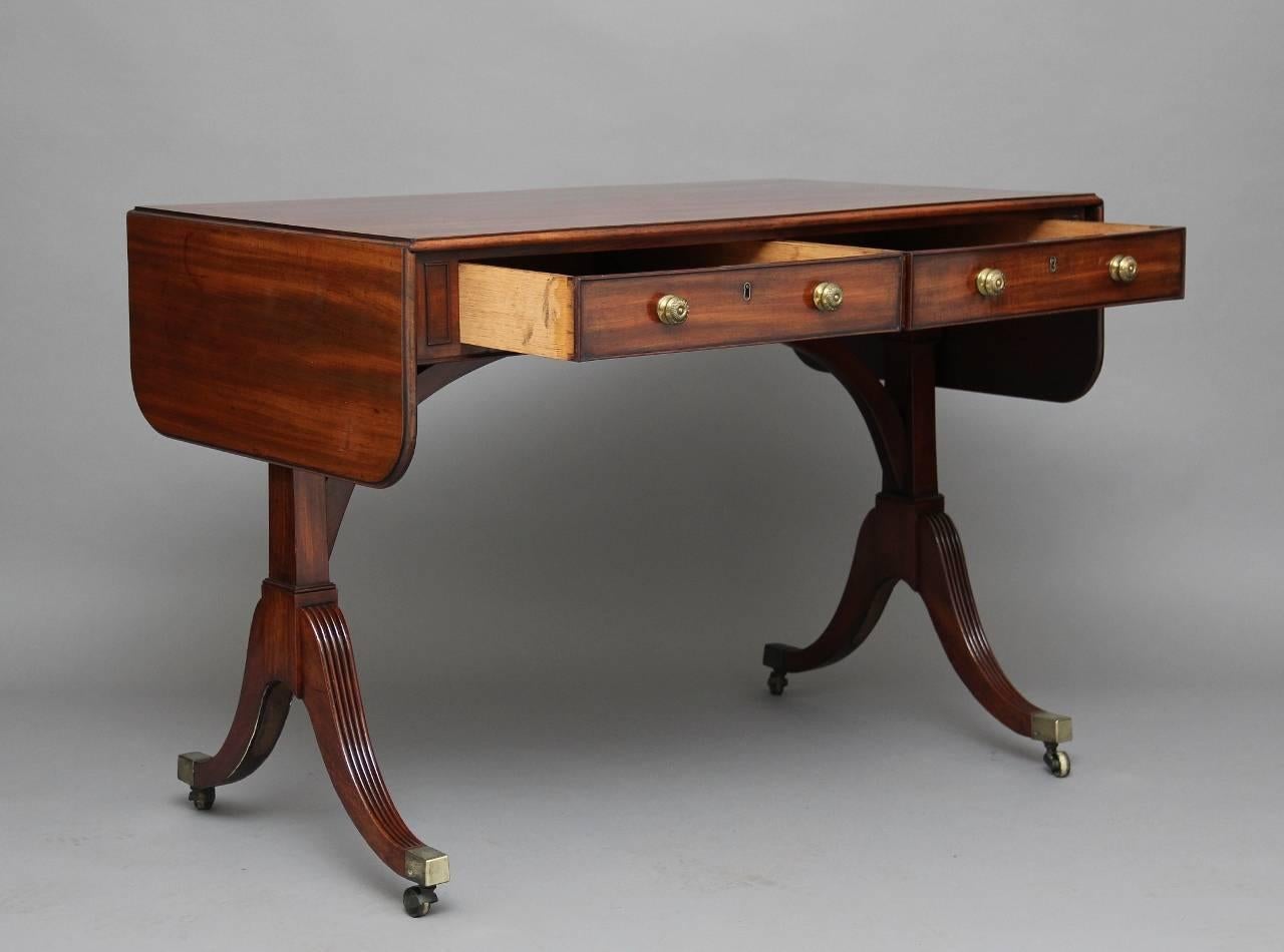 19th century mahogany sofa table, the rounded rectangular twin flap top with a moulded edge above two oak lined drawers with original brass turned knobs, the reverse the same but having dummy drawers, the end supports united with a curved stretcher,
