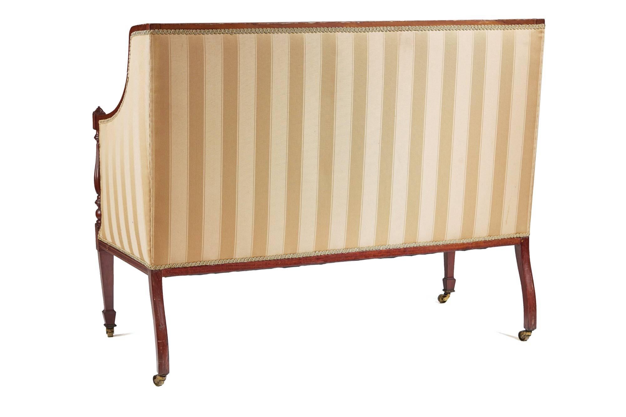 A Fine quality inlaid mahogany settee,with a shaped back framed in inlaid mahogany comes forward to form the arms,shaped reeded turned supports with carved finals, cushion seat,inlaid tapering front leg with shaped back legs,with original brass