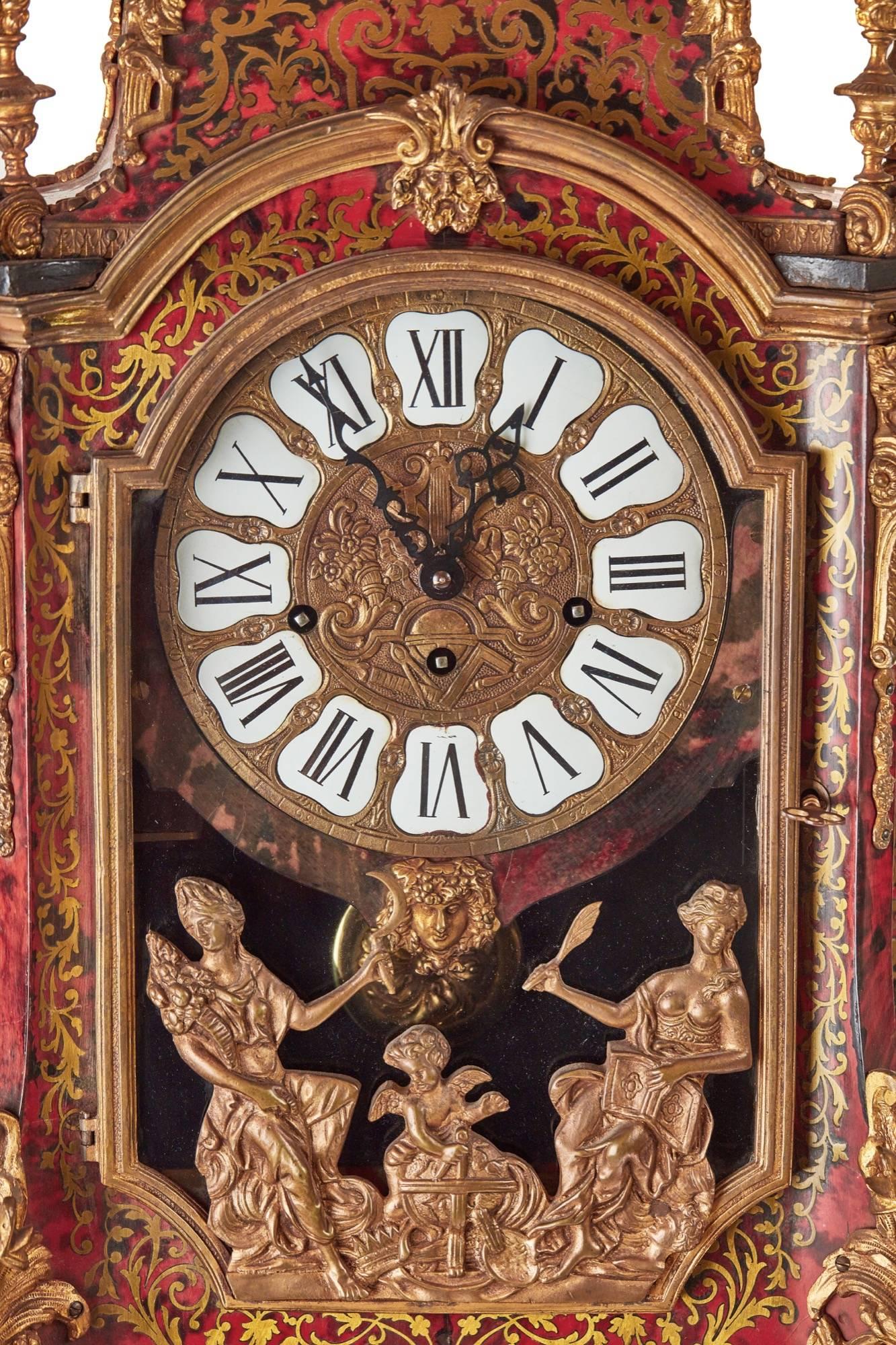 A fine French boulle clock on a boulle consul table, the top having an ormolu figure, with ormolu finals, red tortoiseshell with boulle inlaid work, shaped sides to the clock, enamel and brass dial with a three trained movement, supported by four