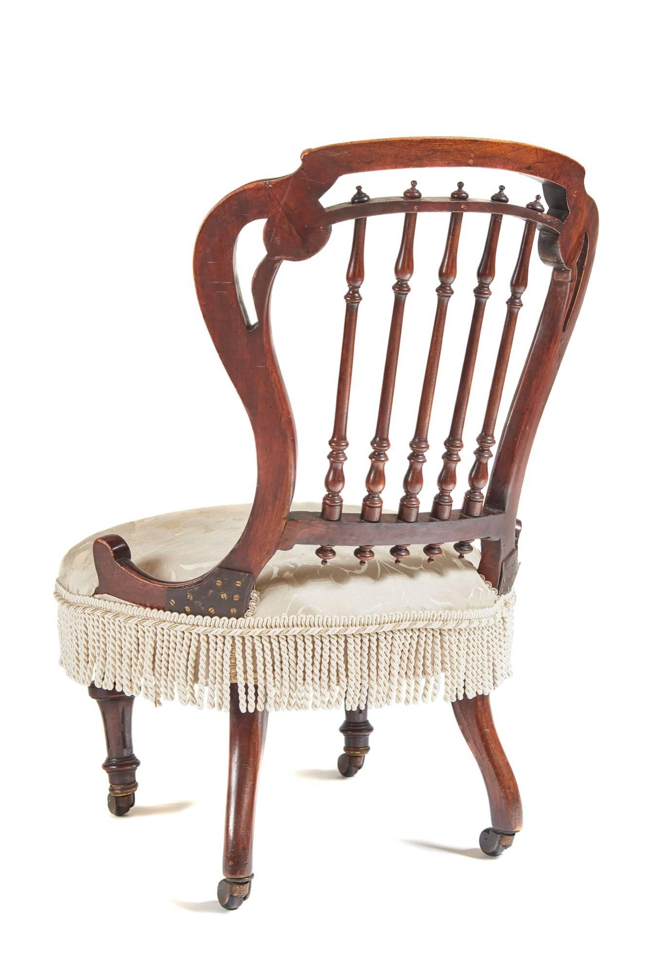 Unusual Victorian walnut nursing chair with carved walnut shaped frame turned carved spindles to the back, newly re-upholstered seat, supported by turned fluted front legs outswept back legs, original ceramic castors.

Measures: Height: