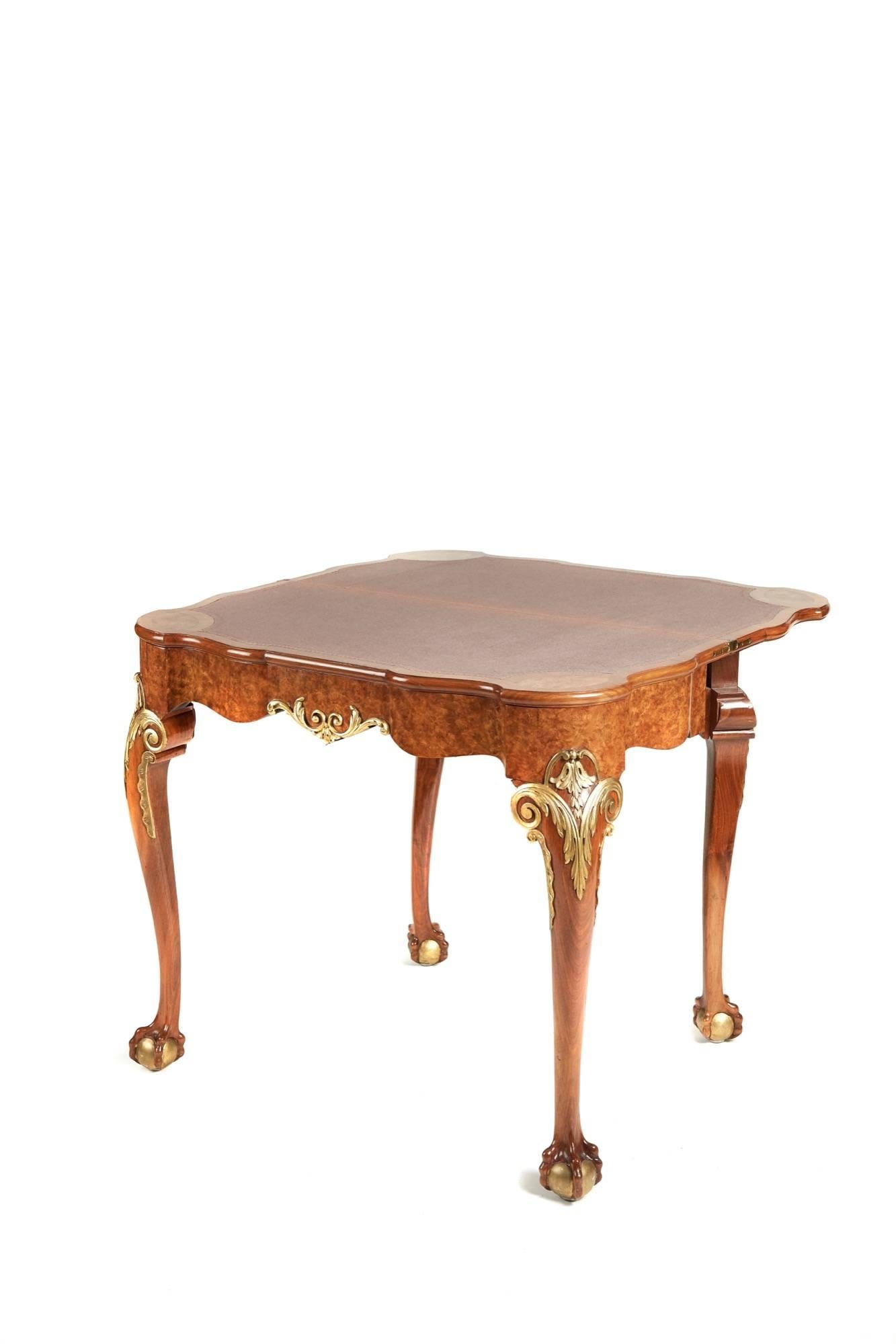 A George II style burr walnut and giltwood card table, the shaped burr walnut top opens to reveal a baize interior, lovely shaped burr walnut and carved giltwood frieze, with acanthus carved knees and cabriole legs on giltwood claw and ball