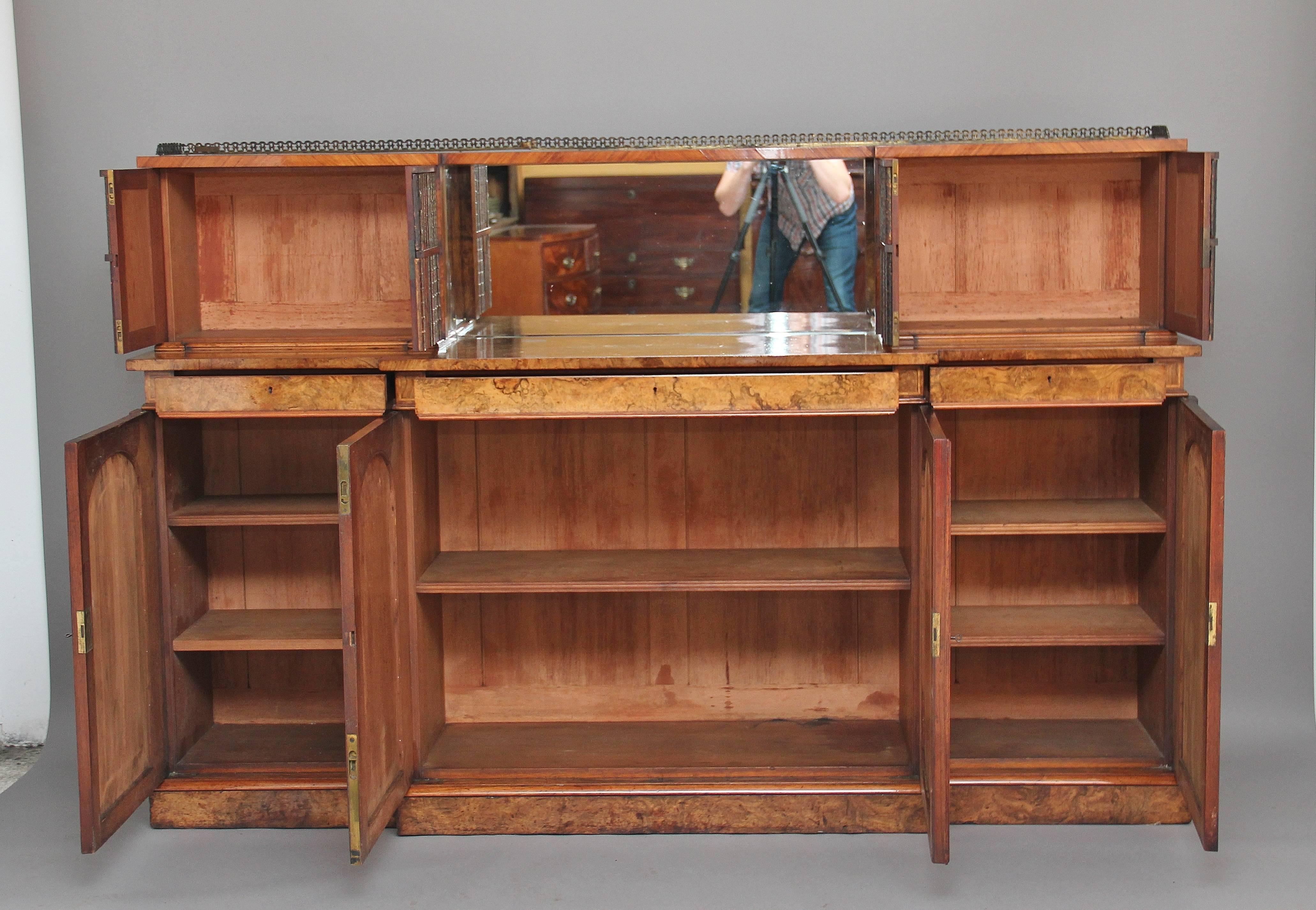 A fantastic quality 19th century burr walnut cabinet, the top section having a brass gallery running along the back and sides, with a mirror below flanked by cupboards either side with the door fronts decorated with book spines, the top of the