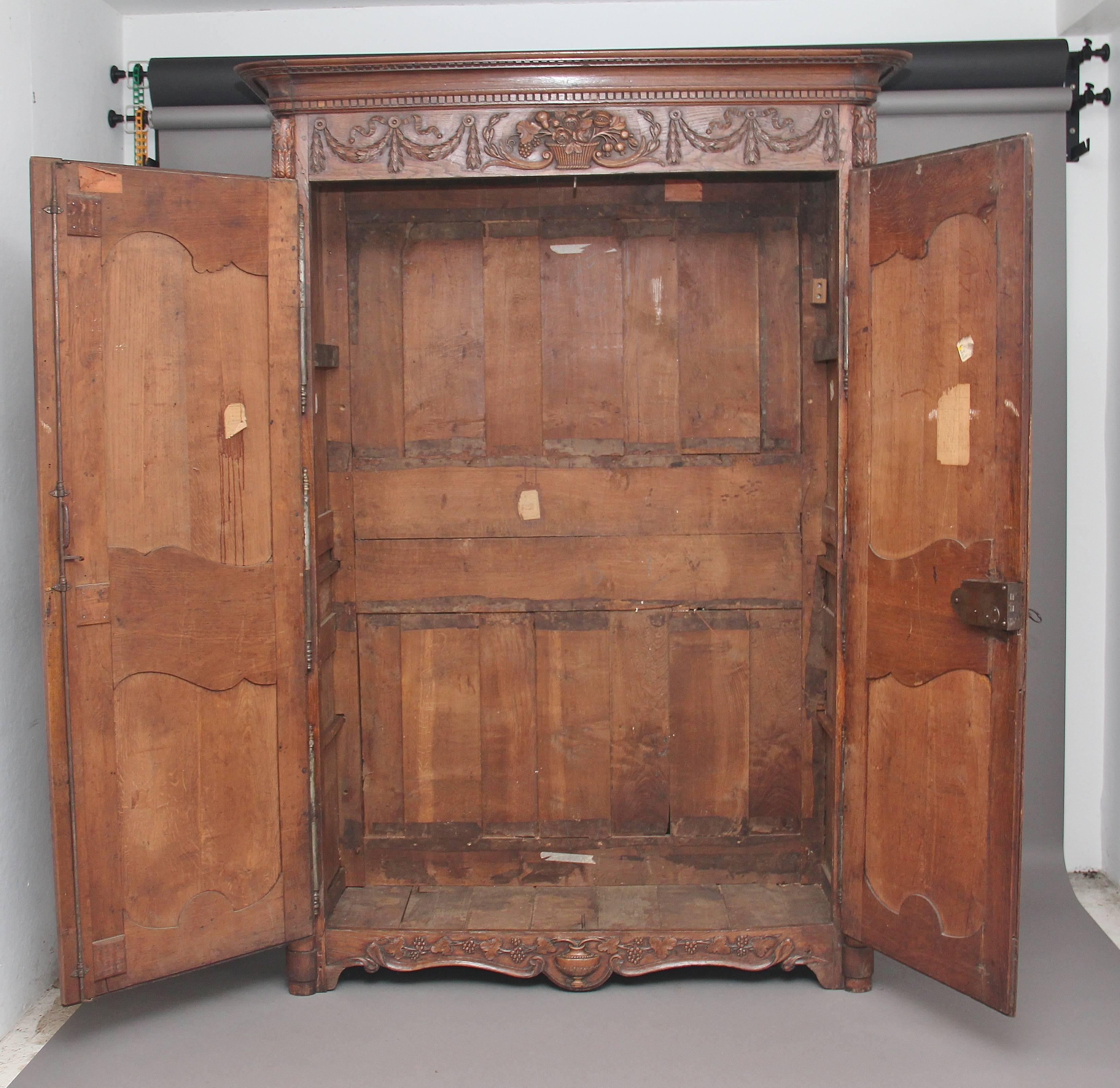 Early 19th century French oak marriage armoire from the Normandy region, the shaped and carved cornice with a frieze below with lovely crisp carvings of a basket of flowers and swags either side, the armoire having two doors each with two fielded