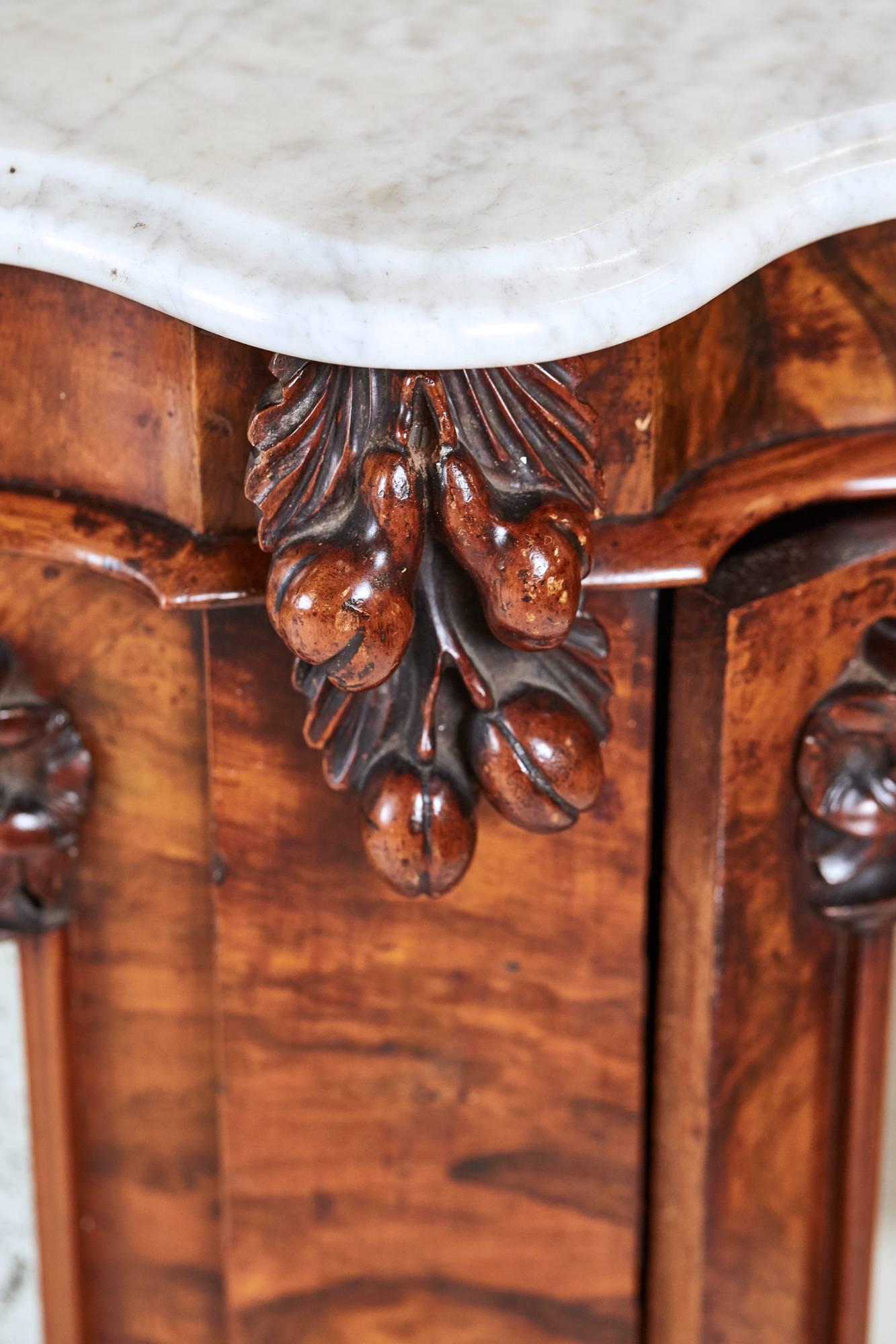 A Victorian figured walnut marble top mirror back credenza of serpentine outline, a shaped mirror back with solid carved walnut decoration above the original white marble top with thumb molded edge, the serpentine carved walnut base with four