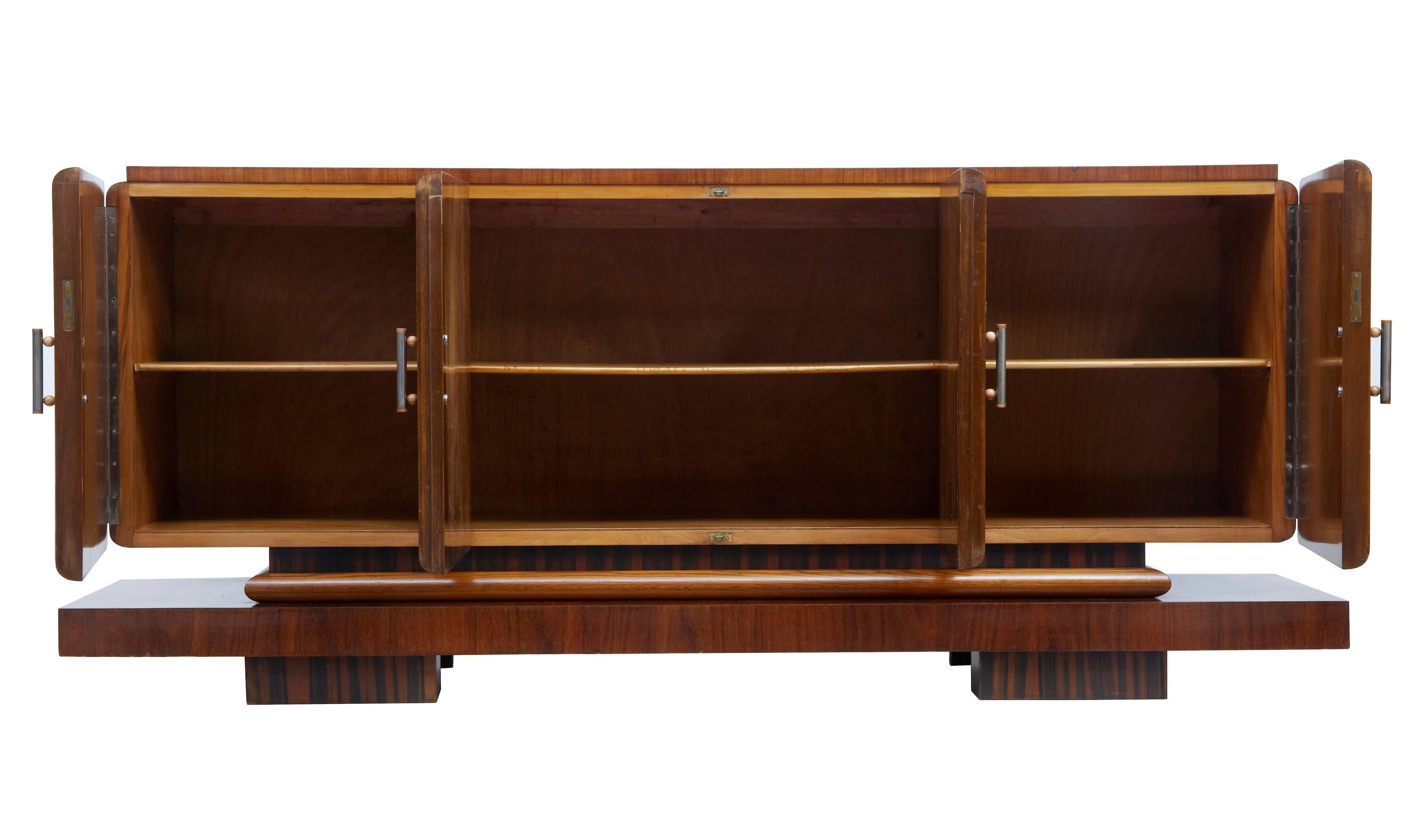 Fantastic Art Deco period sideboard of large proportions, circa 1920.
Four doors with matched walnut veneers which open to a single shelf.
Standing on a kingwood veneered plinth base.
Good rich color.
Ceramic and brushed steel handles.
Some