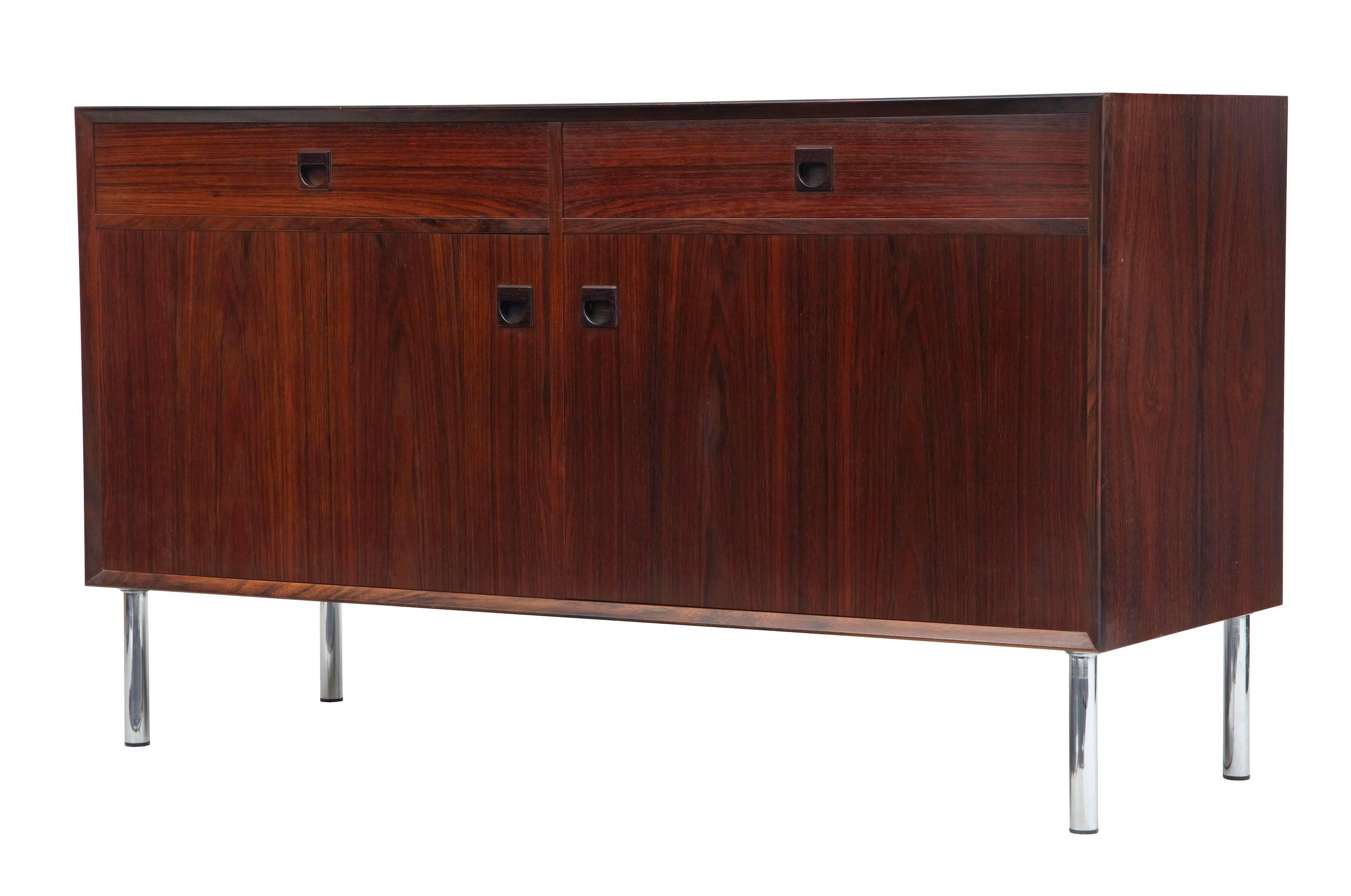 1960s rosewood buffet of good quality.
Fine rosewood veneers.
Two drawers over a double door cupboard.
Standing on chromed legs.
Some surface marks and fading to top and side.

Measures: Height: 30 3/4