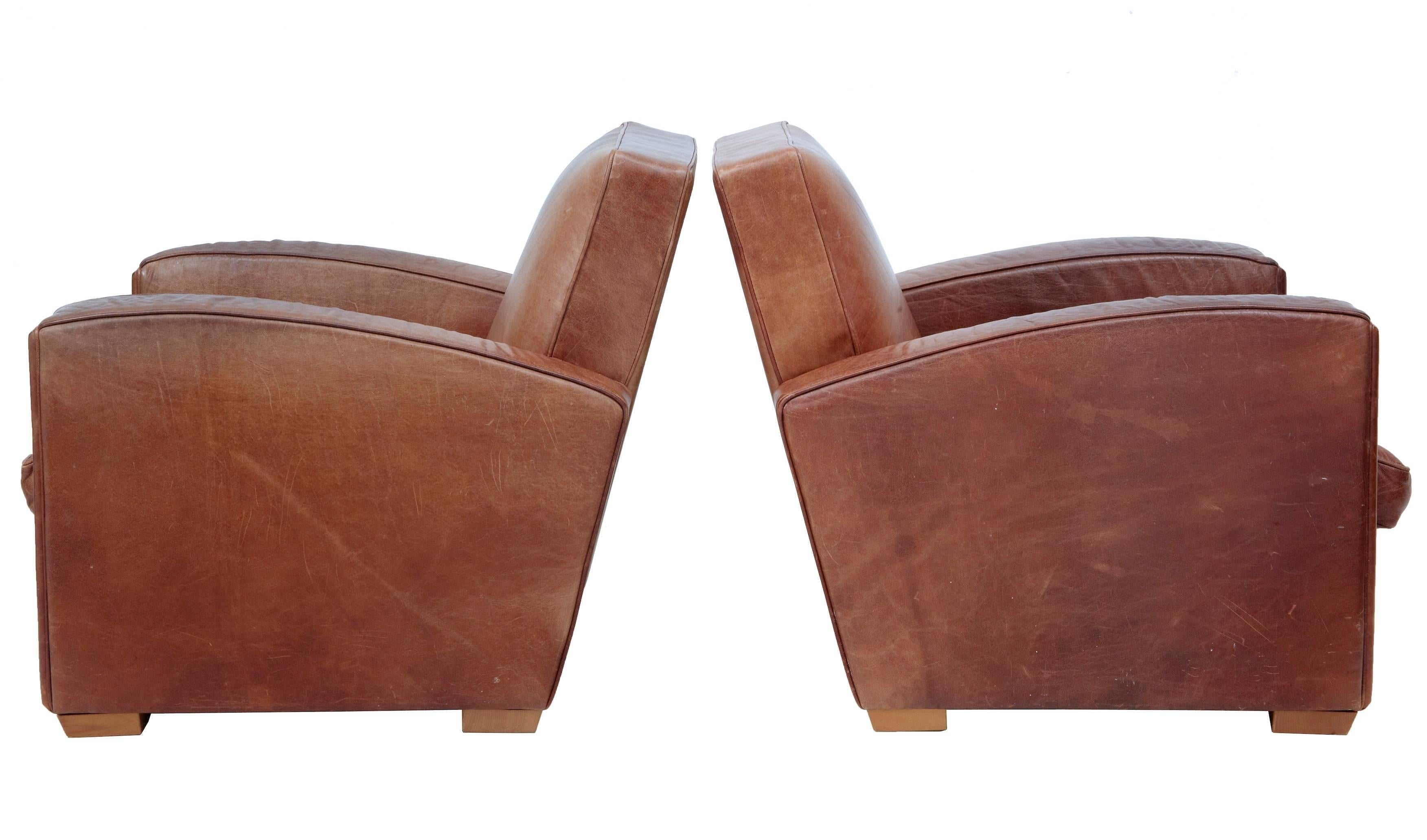 Pair of typical shape Art Deco influenced club armchairs from the late 1960s.
Upholstered in good quality brown leather.
Some staining to the back rests and the odd mark, otherwise in good condition.
Standing on block feet.

Measures: Height 30