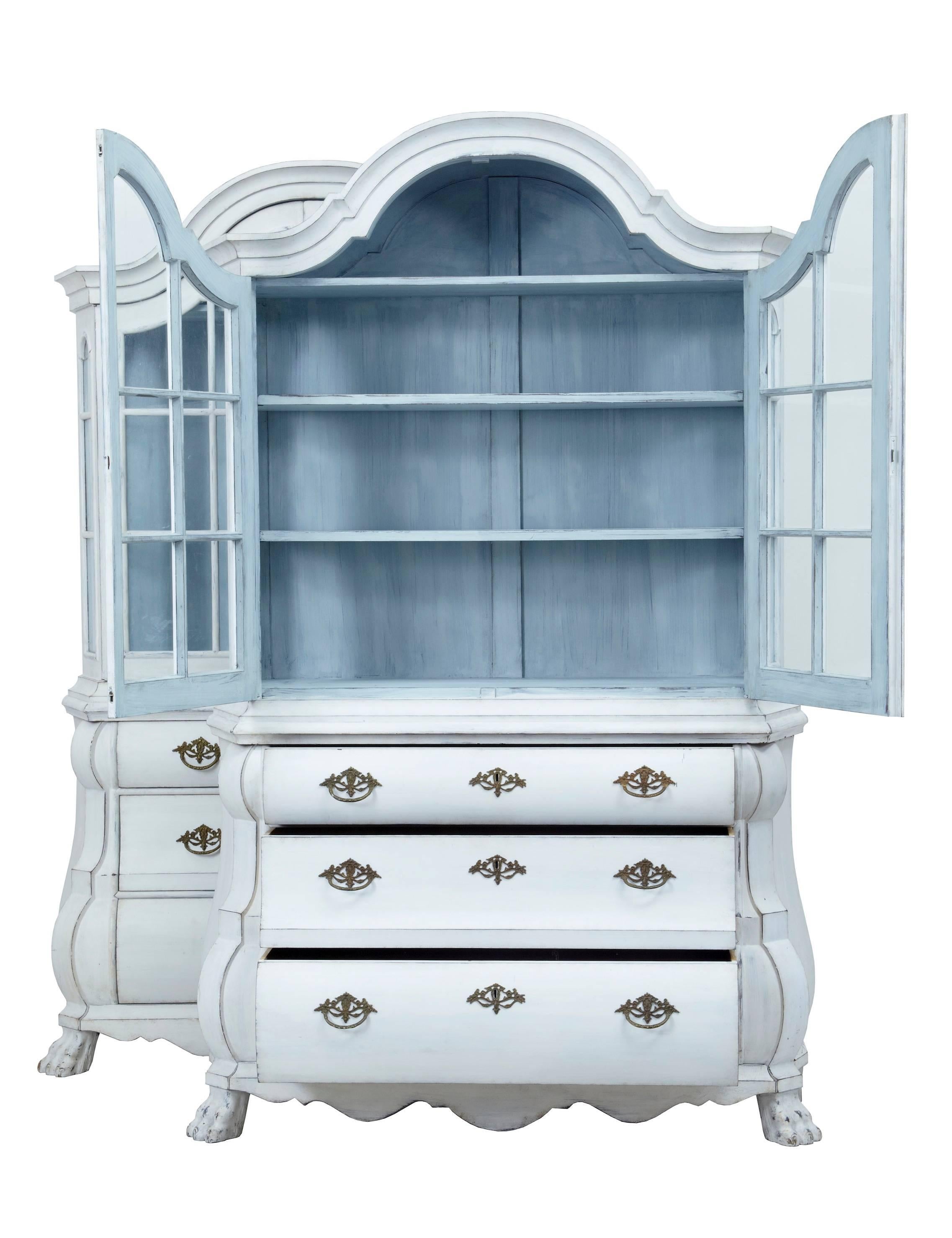 Pair of Dutch later painted vitrines, circa 1895.
Each comprising of two parts.
Top section with shaped cornice, double glazed door opening to three shelves, with light faded blue painted interiors.
Bottom sections of bombe shape, each with three