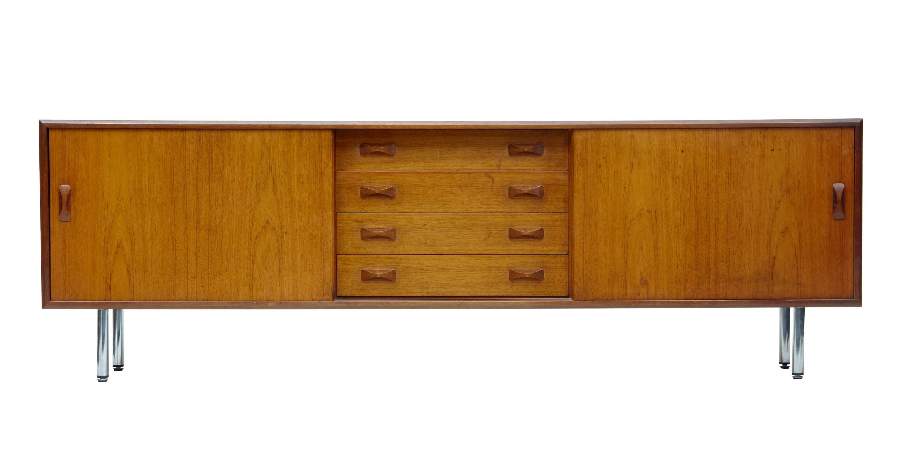 Good quality Danish teak sideboard by Danish makers clausen and sons, circa 1960.
Central bank of four drawers, flanked either side by a sliding door to reveal a single shelf.
Good colour and patina.
Standing on four chromed legs.
Some surface