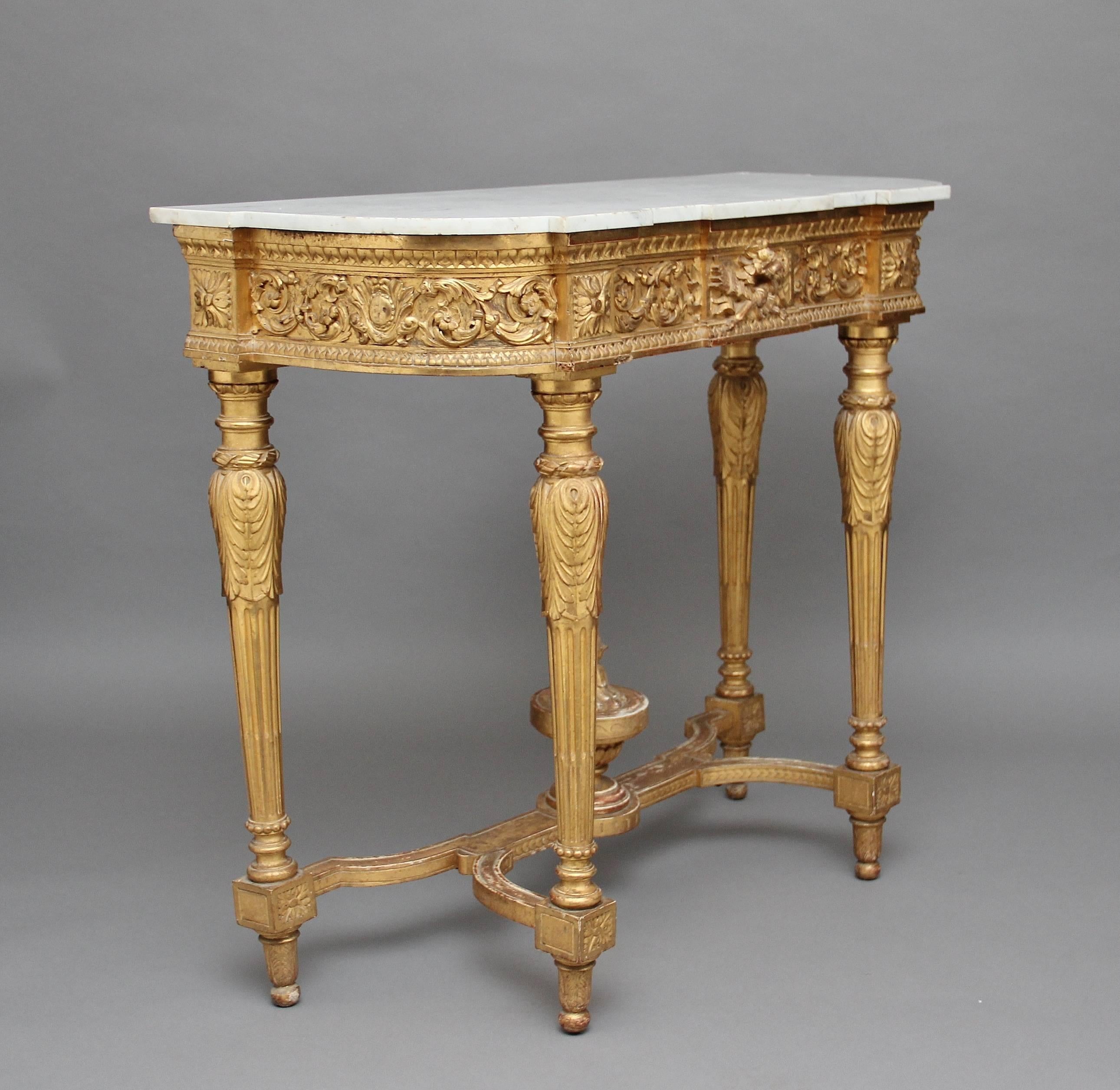 19th century gilt and marble-top consol table of good proportions, the shaped white marble top resting on the frieze which is profusely carved with floral decoration, with four carved and fluted legs supported by a shaped stretcher with a bold